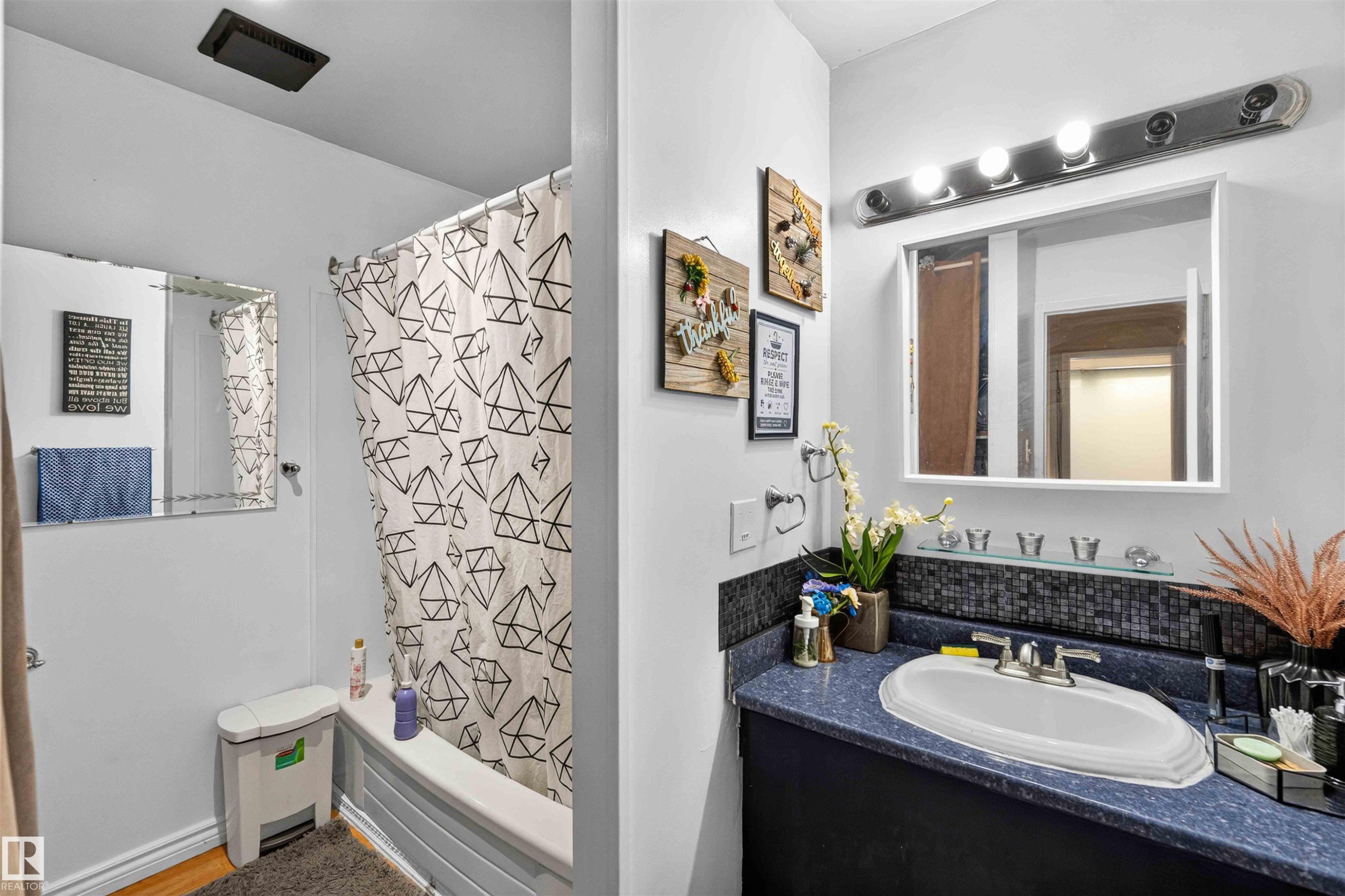 Built-in bathtub with shower, vanity with integrated sink, mounted medicine cabinet, and overhead light fixture - 17127 109 Street Nw, Edmonton, AB - Indoor Photo Showing Bathroom
