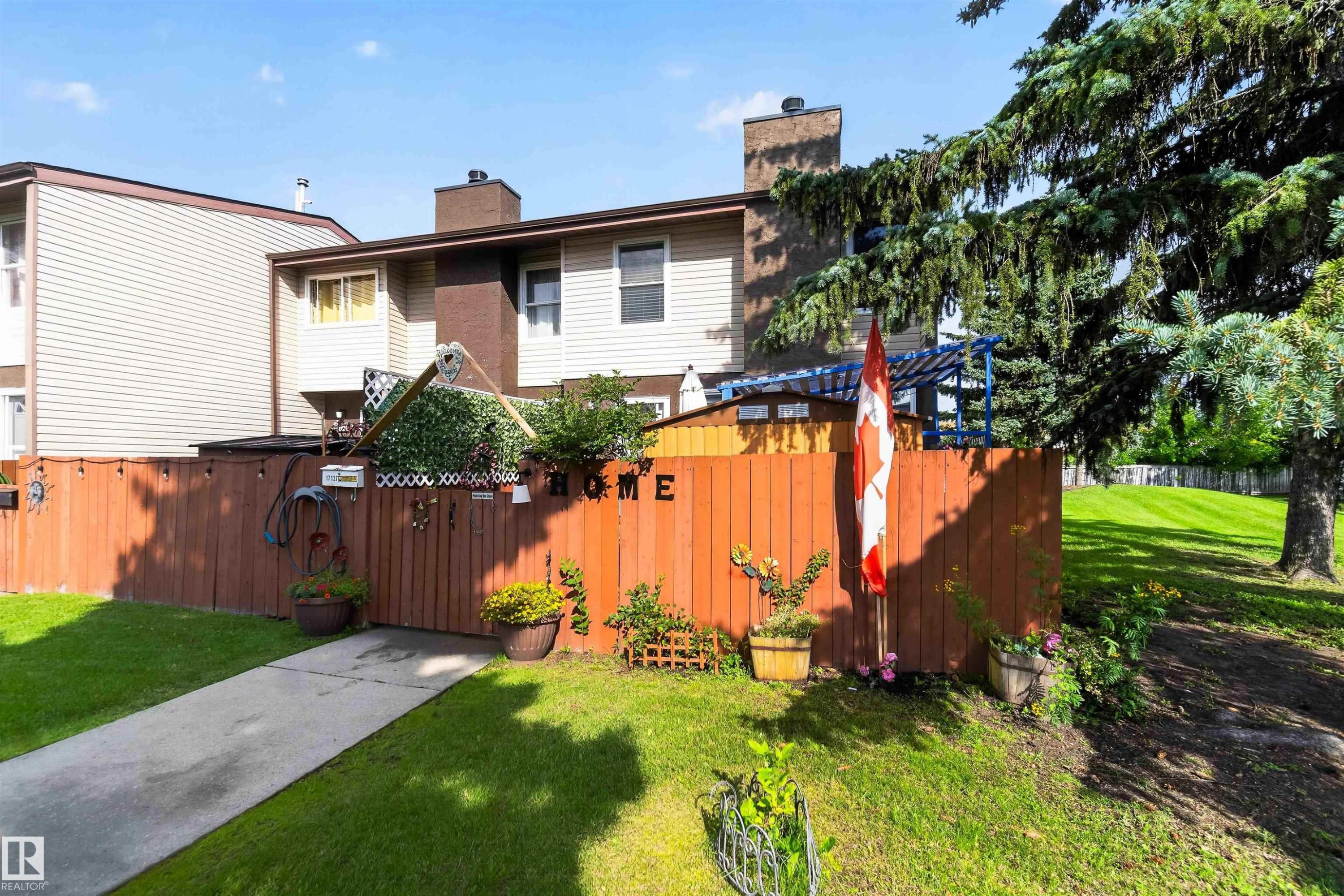 Fenced yard featuring a concrete walkway, mature tree, and adjacent green space - 17127 109 Street Nw, Edmonton, AB - Outdoor