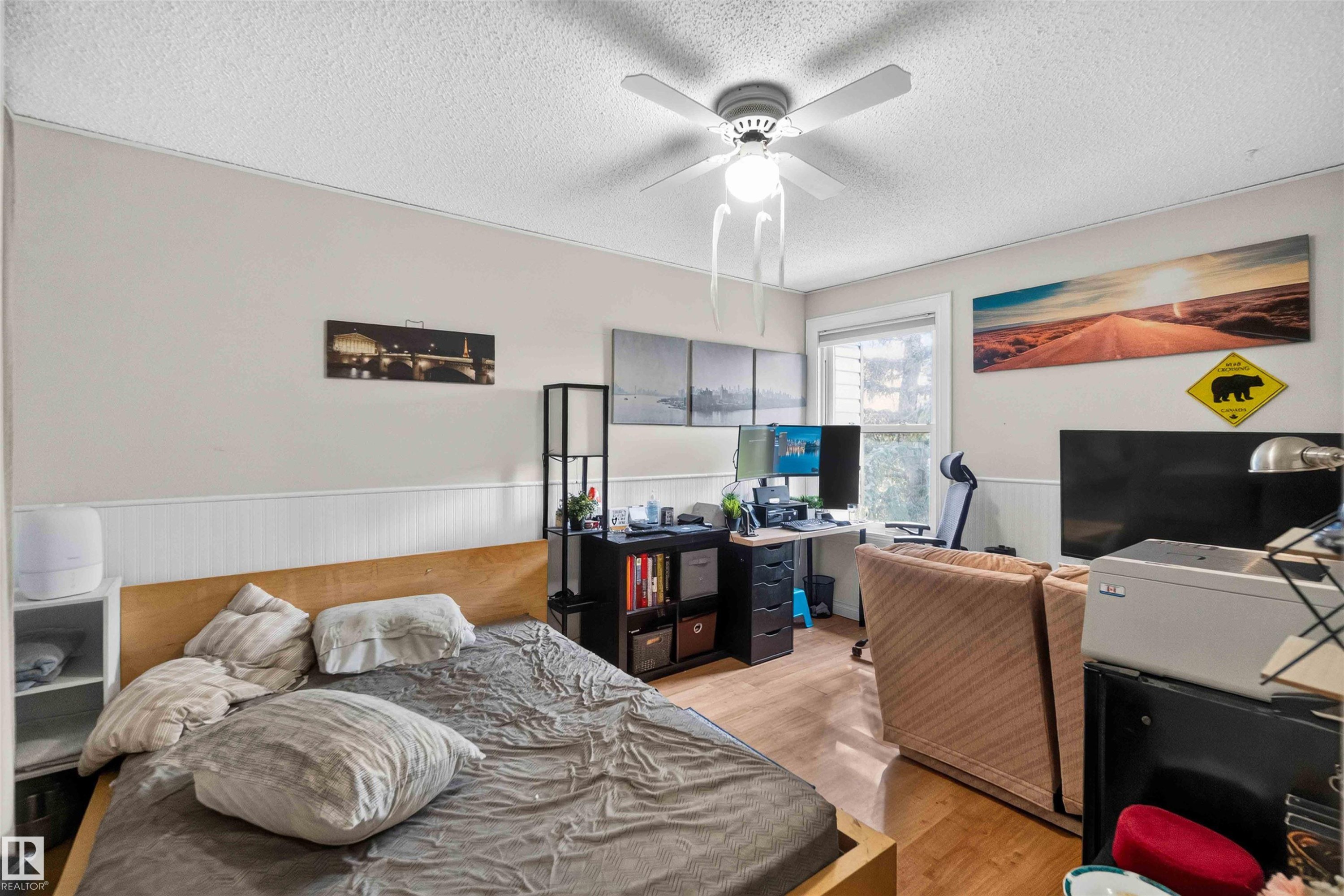 Wood-finish flooring, ceiling fan, window with natural light, and wainscoting detail - 17127 109 Street Nw, Edmonton, AB - Indoor Photo Showing Bedroom