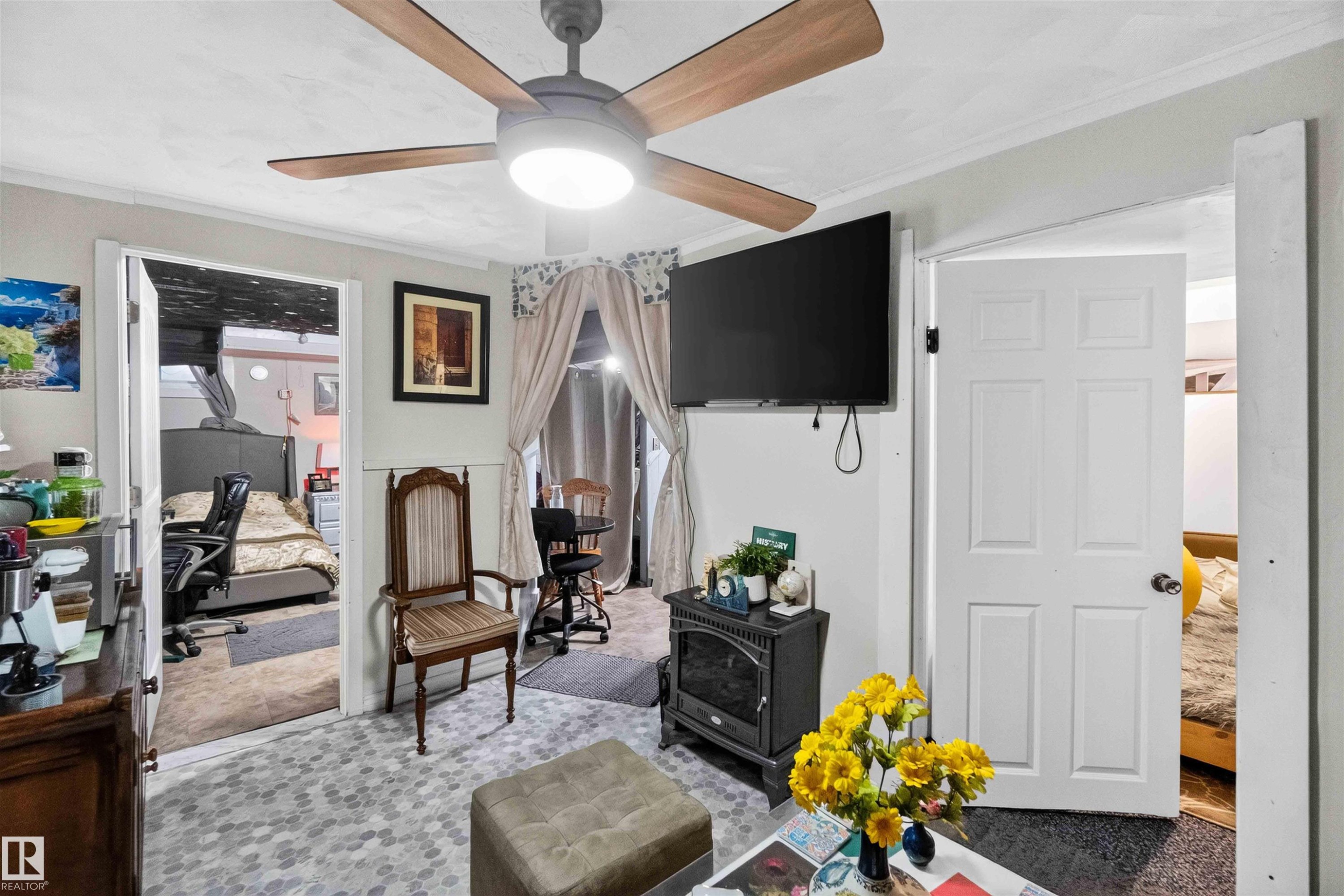 Ceiling fan with light fixture, wall-mounted television, and a decorative electric fireplace - 17127 109 Street Nw, Edmonton, AB - Indoor