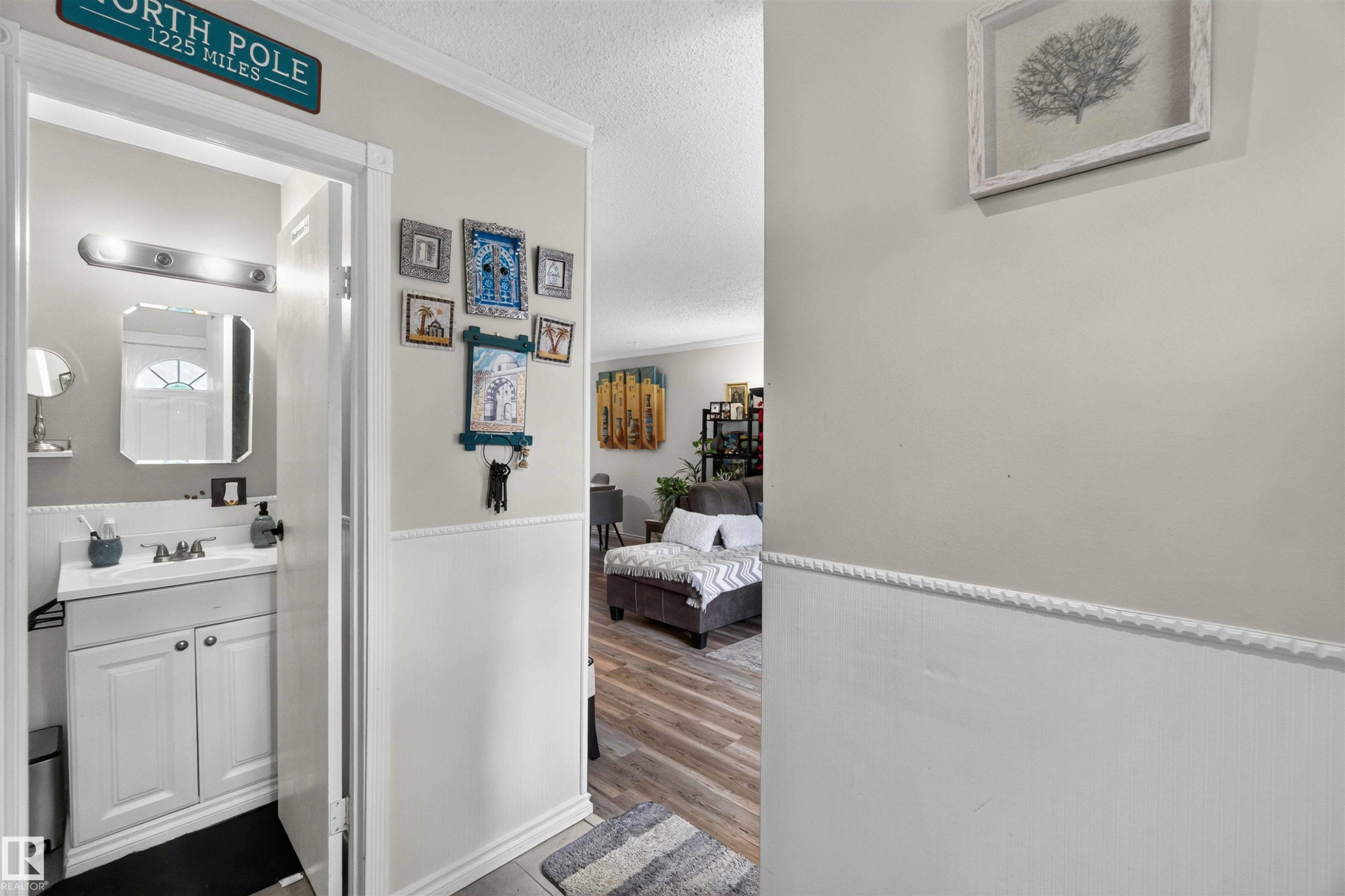 Bathroom featuring a white vanity with built-in cabinetry, an undermount sink, and a framed mirror, complemented by a brushed nickel light fixture - 17127 109 Street Nw, Edmonton, AB - Indoor Photo Showing Bathroom