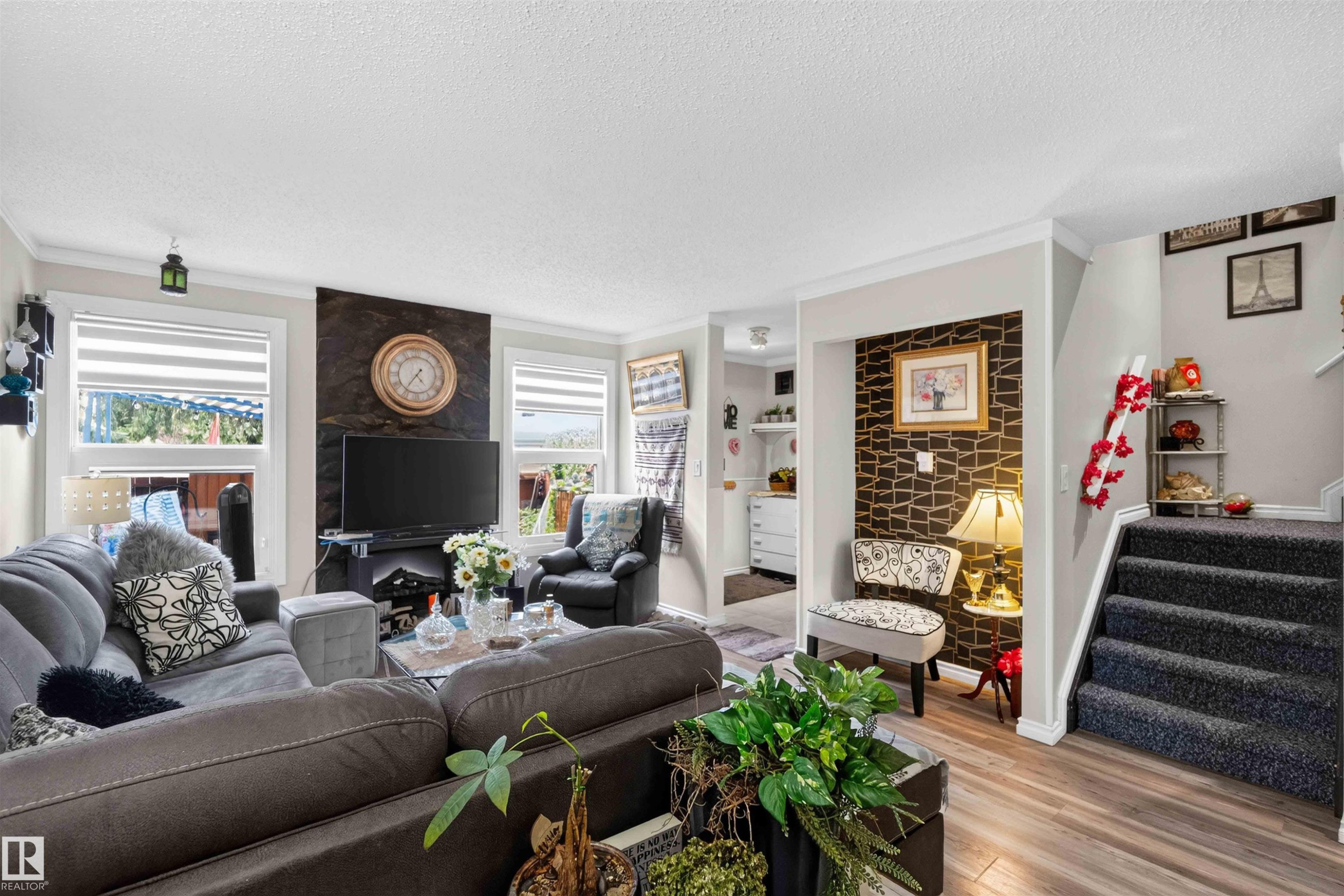 Wood-finish flooring, accent wall with textured finish, contrasting wall decor, built-in shelving, carpeted stairs - 17127 109 Street Nw, Edmonton, AB - Indoor Photo Showing Living Room