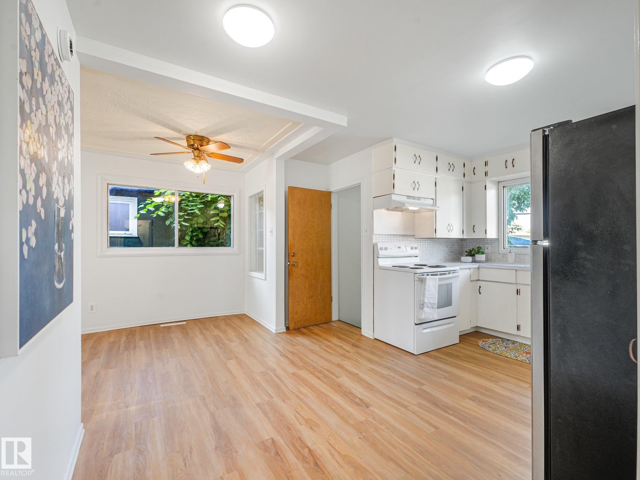 Kitchen with white cabinetry, white electric range, and wood-finish flooring - 6112 105A Street Nw, Edmonton, AB - Indoor Photo Showing Kitchen