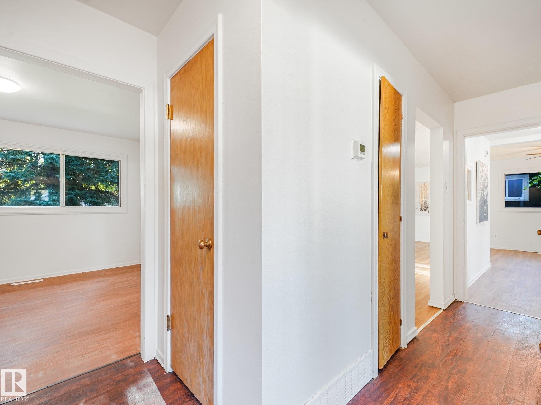 Hardwood-look flooring throughout, solid wood doors, and white walls - 6112 105A Street Nw, Edmonton, AB - Indoor Photo Showing Other Room