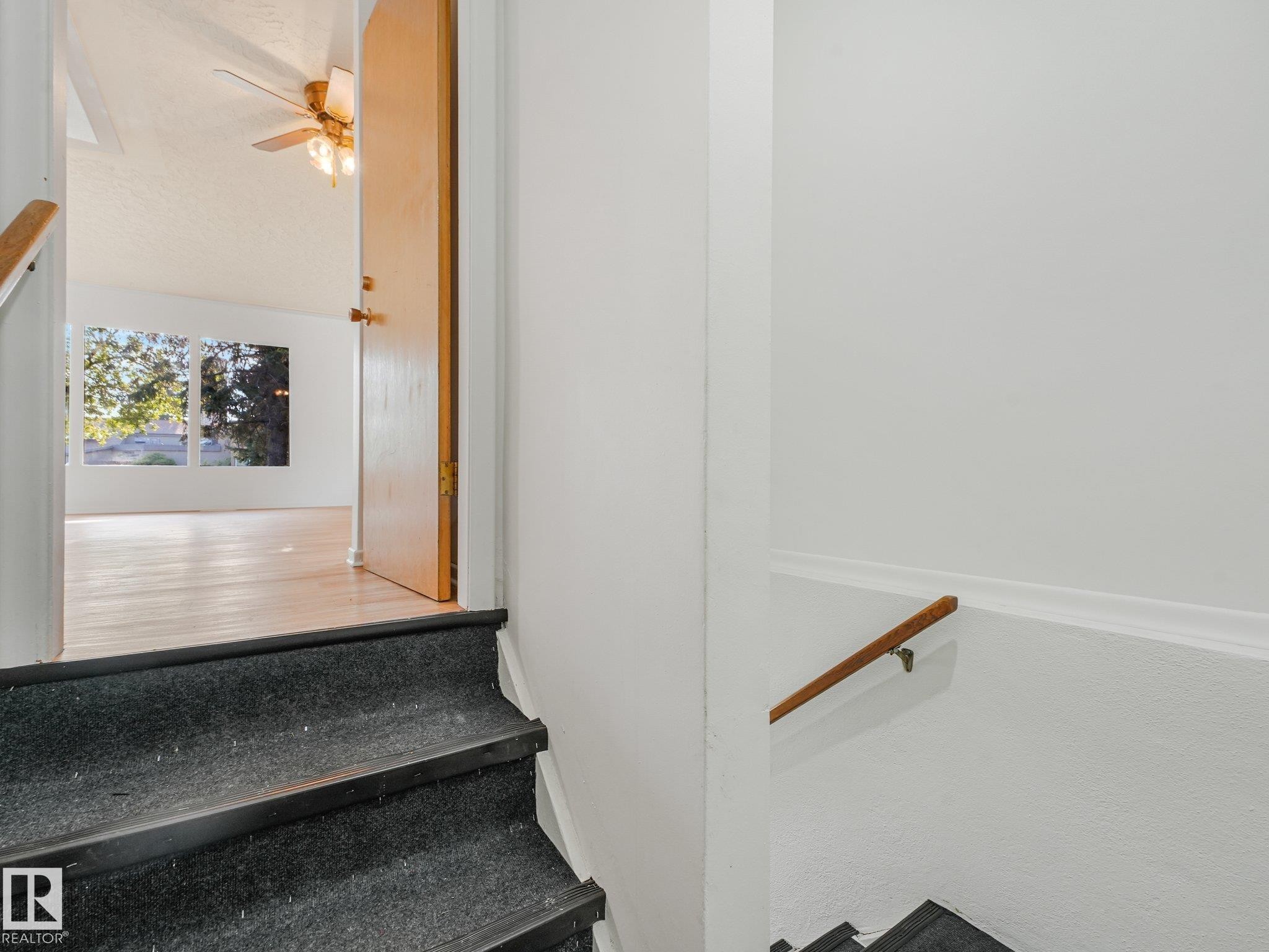 Entryway featuring carpeted stairs, a wooden handrail, and a solid wood door - 6112 105A Street Nw, Edmonton, AB - Indoor Photo Showing Other Room