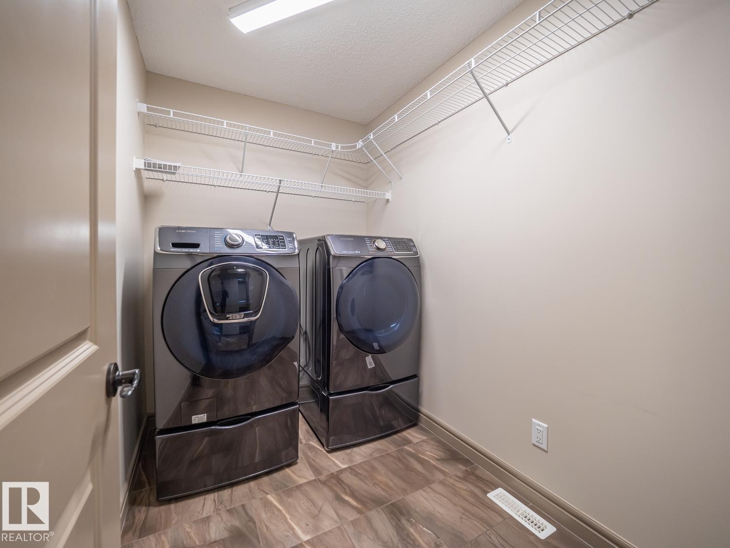 Dedicated laundry space featuring tile flooring, neutral wall tones, and overhead wire shelving - 97 Astoria Point(E), Devon, AB - Indoor Photo Showing Laundry Room