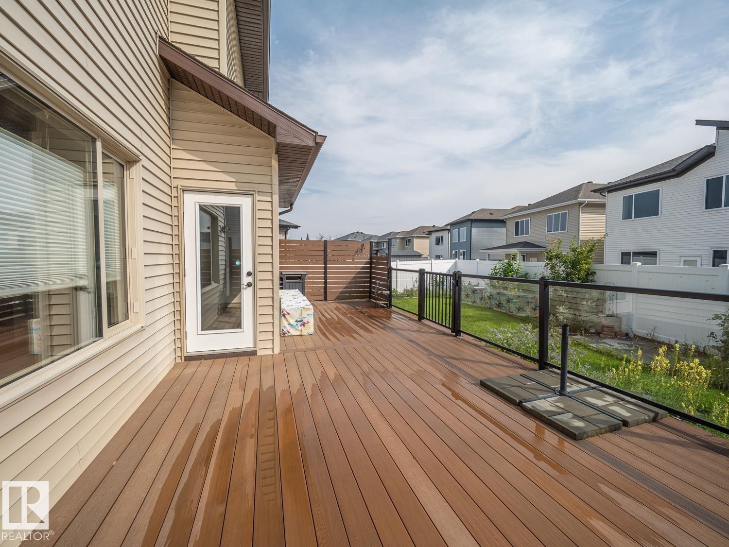 Expansive deck featuring wood-finish planks and a glass panel railing - 97 Astoria Point(E), Devon, AB - Outdoor With Deck Patio Veranda With Exterior
