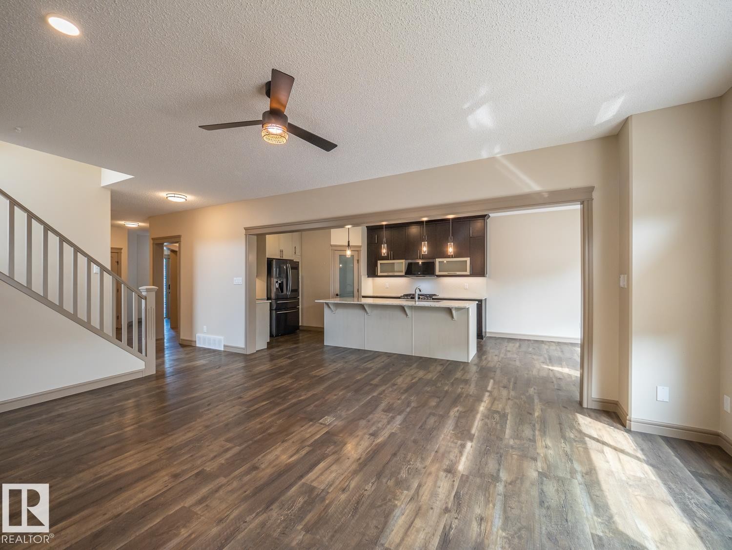 Open-concept design, wood-finish flooring, recessed lighting, ceiling fan, and a kitchen featuring an island with pendant lighting - 97 Astoria Point(E), Devon, AB - Indoor Photo Showing Kitchen