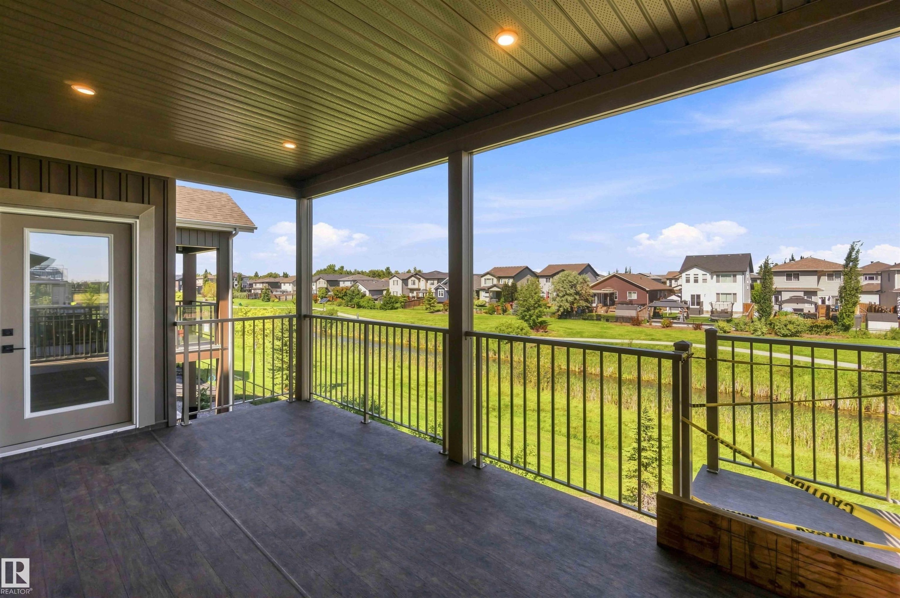Covered outdoor patio with dark composite decking, metal railings, and recessed ceiling lighting - 28 Harley Way, Spruce Grove, AB - Outdoor With Deck Patio Veranda With Exterior