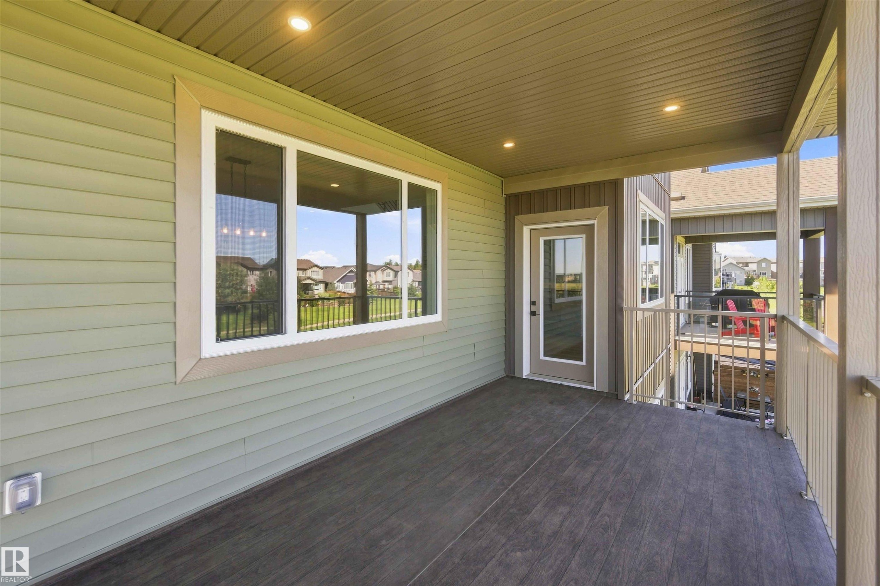 Covered outdoor living space featuring wood-finish flooring, recessed lighting, and a glass-paneled door - 28 Harley Way, Spruce Grove, AB - Outdoor With Deck Patio Veranda With Exterior