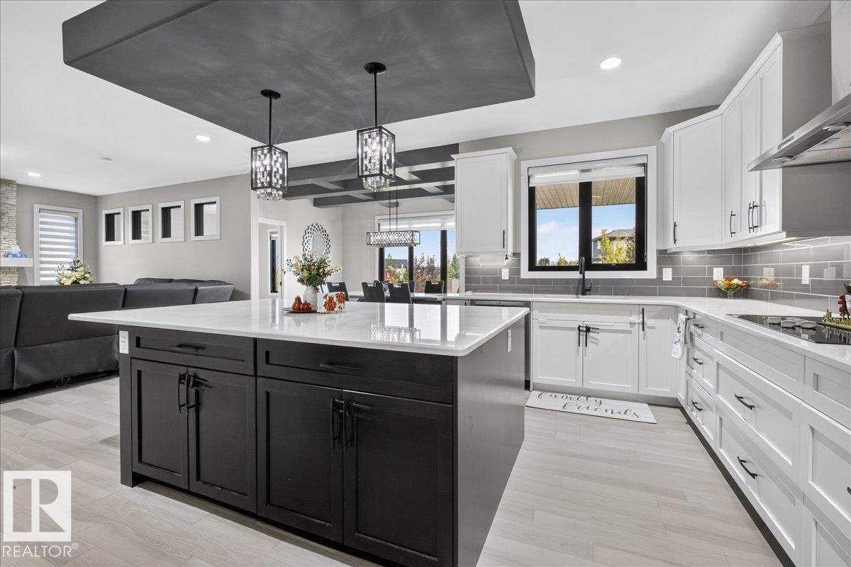 Kitchen featuring a central island with dark cabinetry, white countertops, subway tile backsplash, and light wood-finish flooring - 6813 Knox Loop Sw, Edmonton, AB - Indoor Photo Showing Kitchen With Upgraded Kitchen