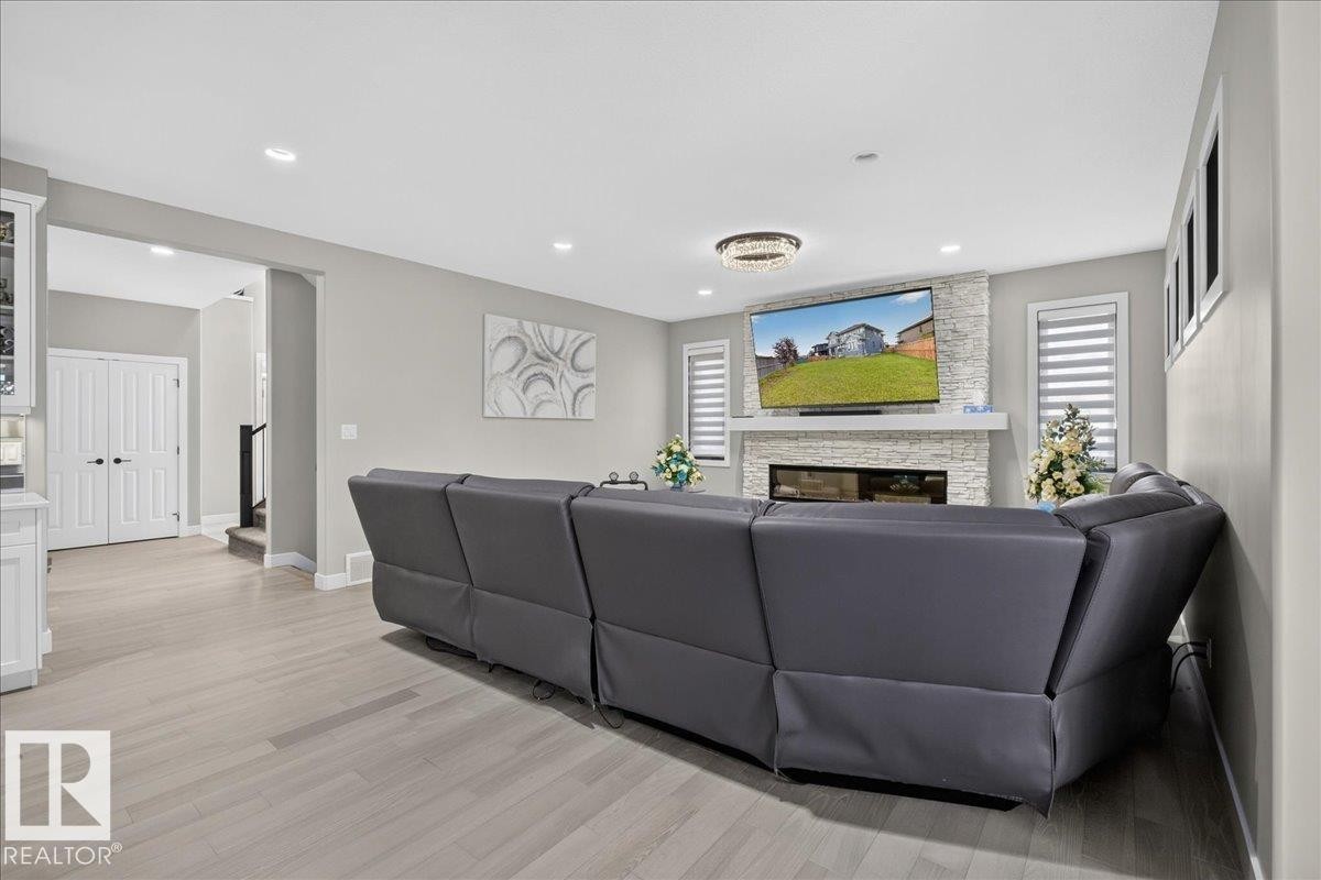 Recessed lighting, wood-finish flooring, and a stacked stone fireplace with a white mantel - 6813 Knox Loop Sw, Edmonton, AB - Indoor Photo Showing Living Room With Fireplace
