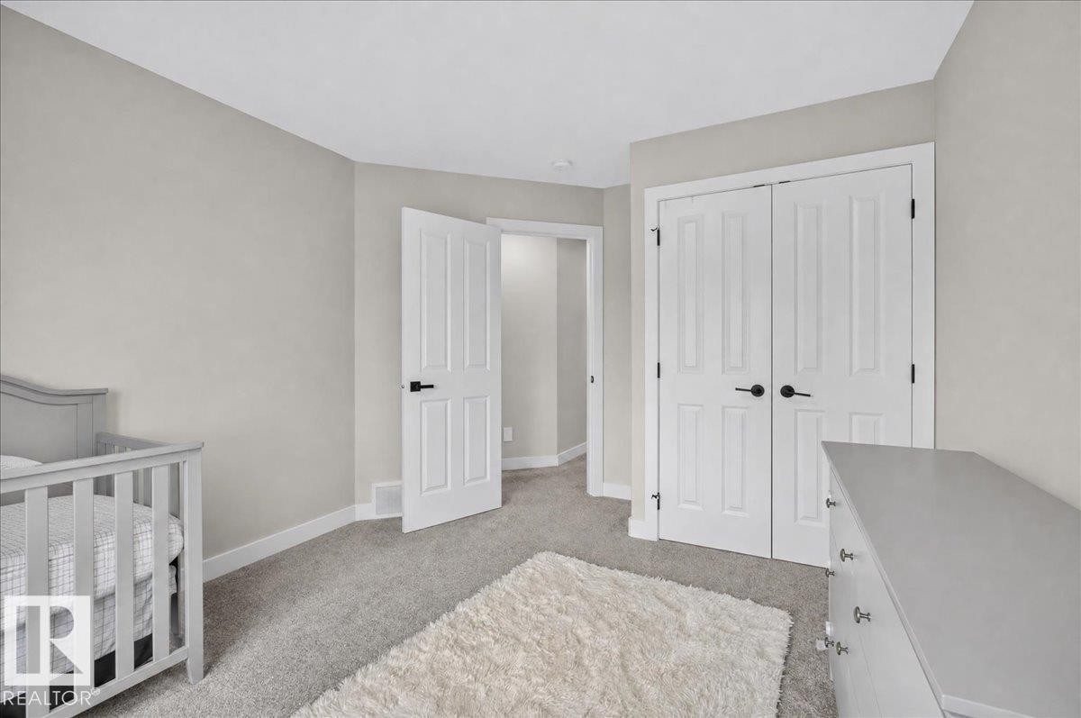 Light gray wall tones with white trim, gray carpeting, and white paneled doors with black hardware - 6813 Knox Loop Sw, Edmonton, AB - Indoor Photo Showing Bedroom