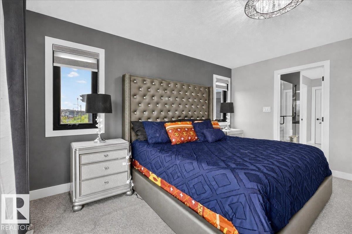 Tufted headboard with upholstered frame, carpeted flooring, and a modern ceiling light fixture - 6813 Knox Loop Sw, Edmonton, AB - Indoor Photo Showing Bedroom