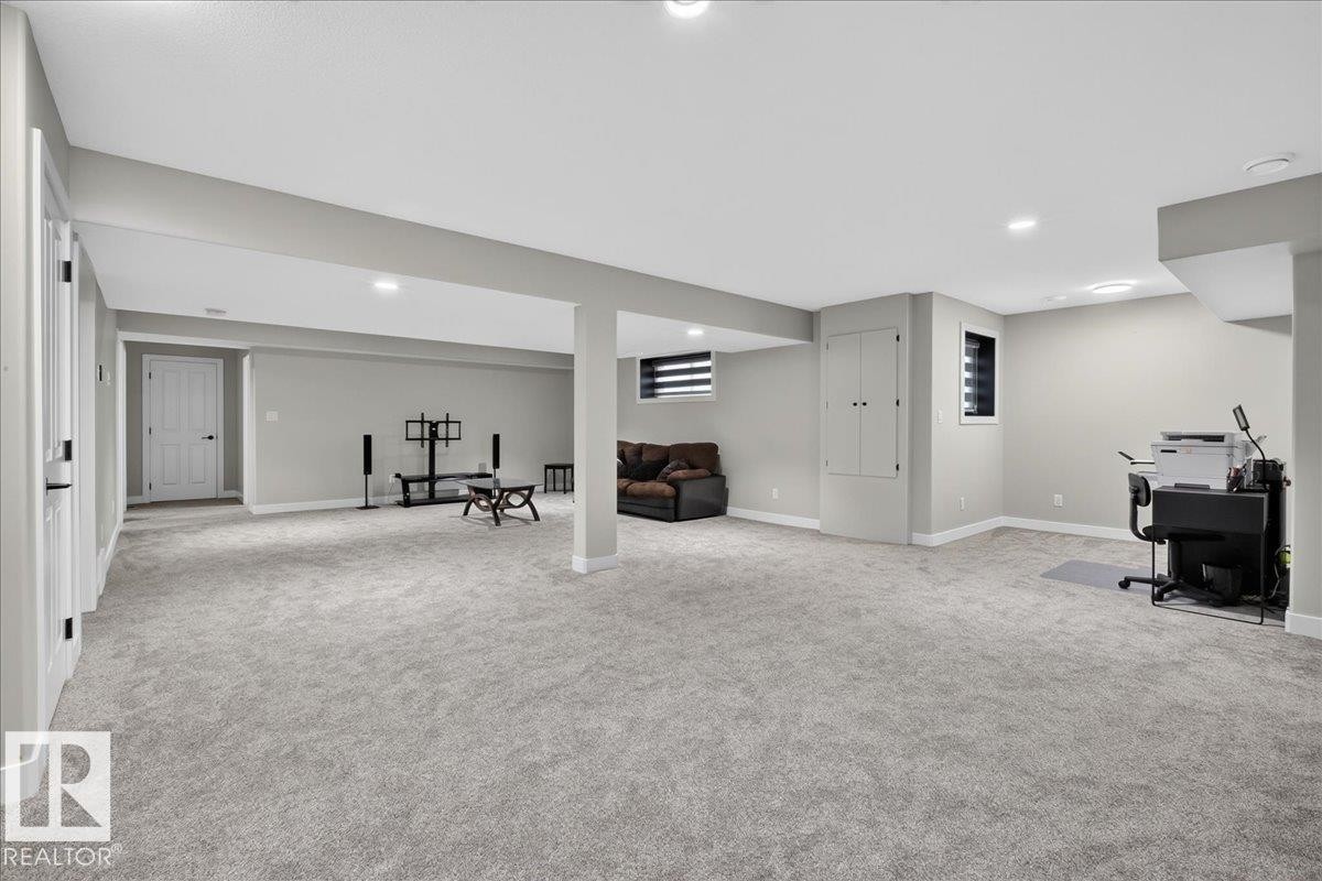 Expansive carpeted area with recessed lighting, two windows with horizontal blinds, and a built-in storage cabinet - 6813 Knox Loop Sw, Edmonton, AB - Indoor