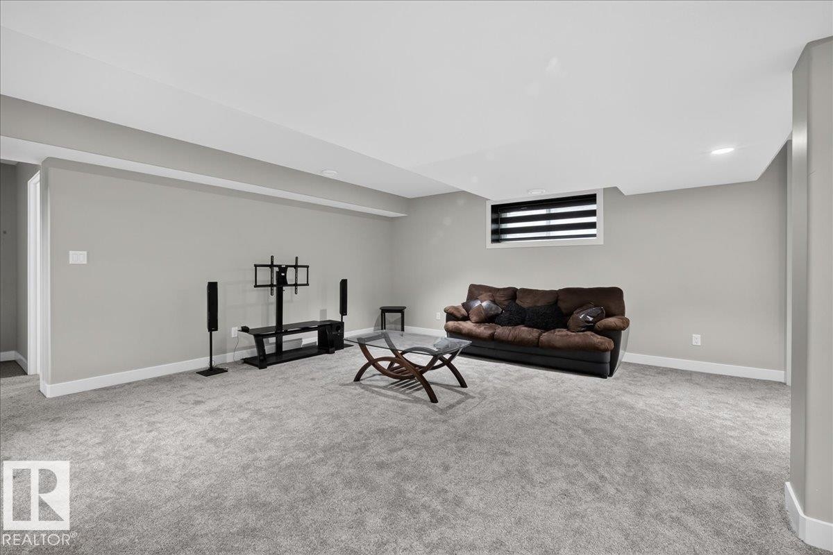 Spacious room featuring gray carpet, light gray walls, white trim, and a window with horizontal blinds - 6813 Knox Loop Sw, Edmonton, AB - Indoor