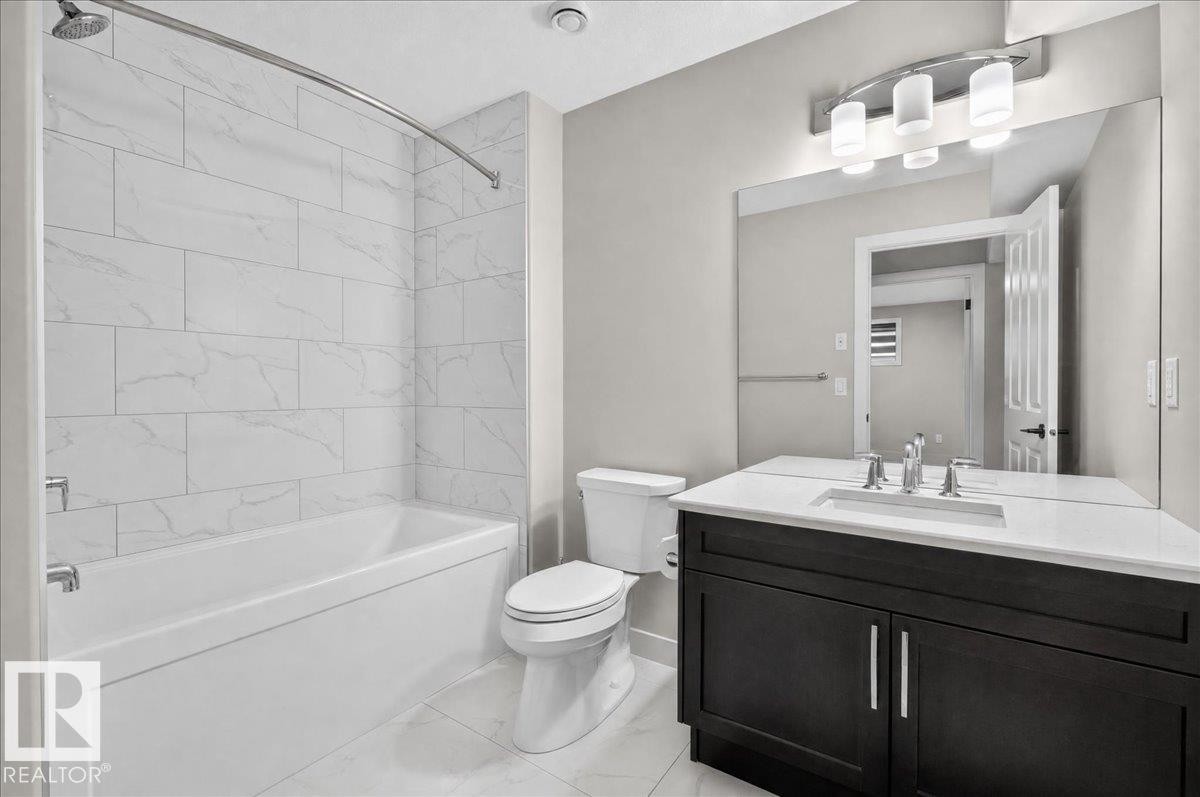 Modern bathroom featuring a single vanity with dark wood-finish cabinetry, a white countertop, and an undermount sink - 6813 Knox Loop Sw, Edmonton, AB - Indoor Photo Showing Bathroom