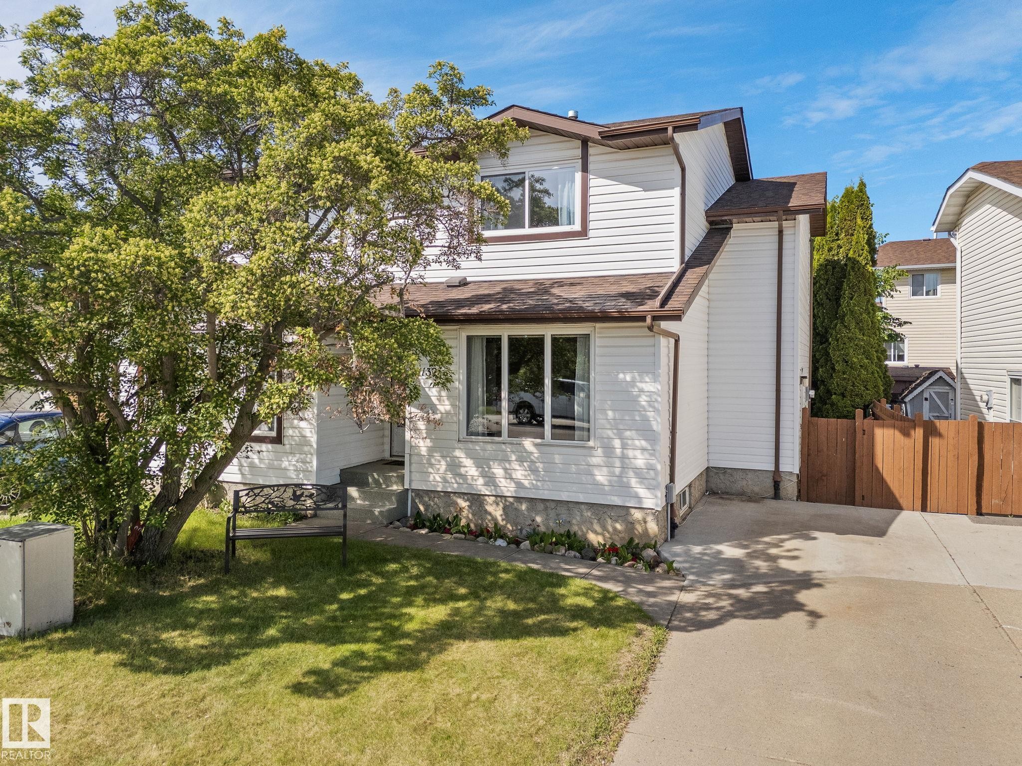 White siding exterior with brown trim, brown shingle roof, paved driveway, and mature landscaping - 17132 103 Street Nw, Edmonton, AB