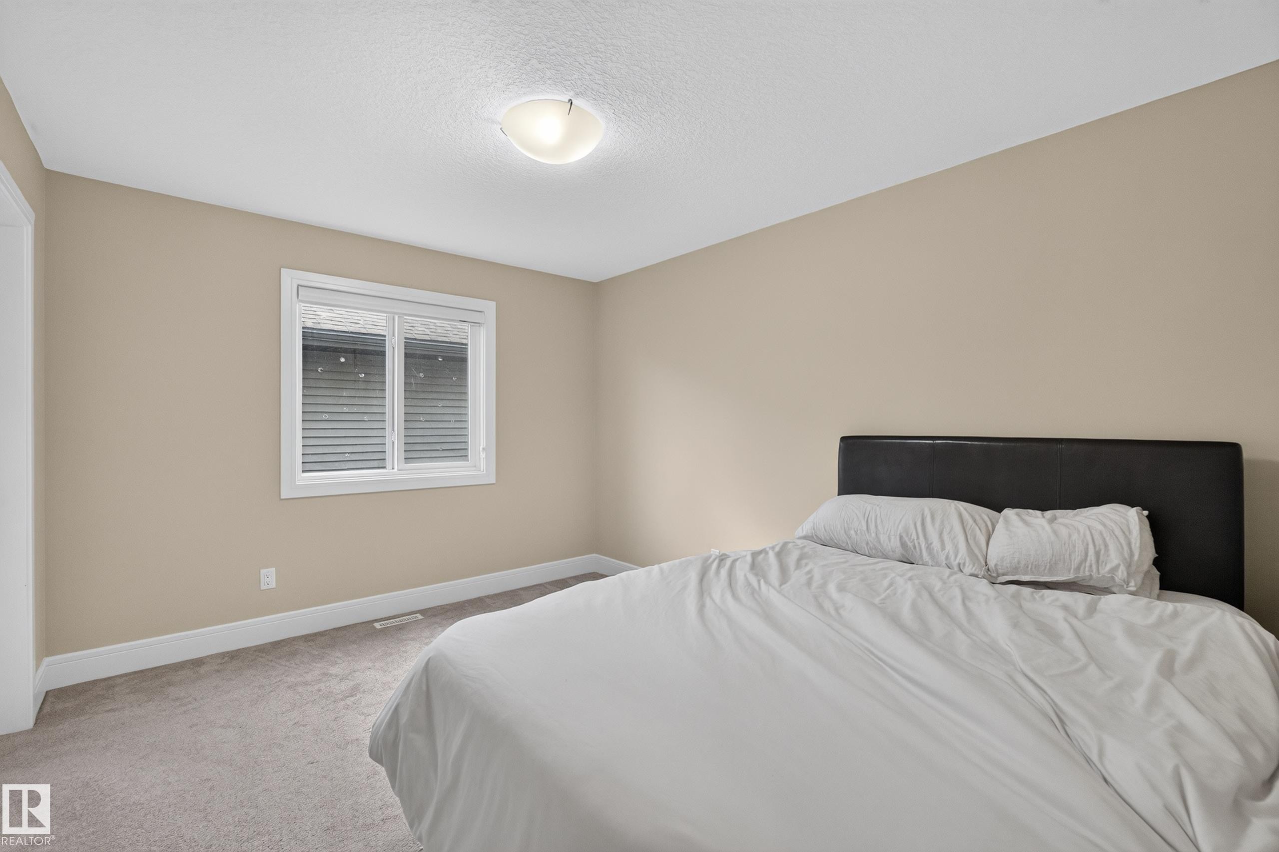 Carpeted flooring, neutral wall paint, white window trim, white baseboards, and a flush mount ceiling light fixture - 7014 Chivers Loop Sw, Edmonton, AB