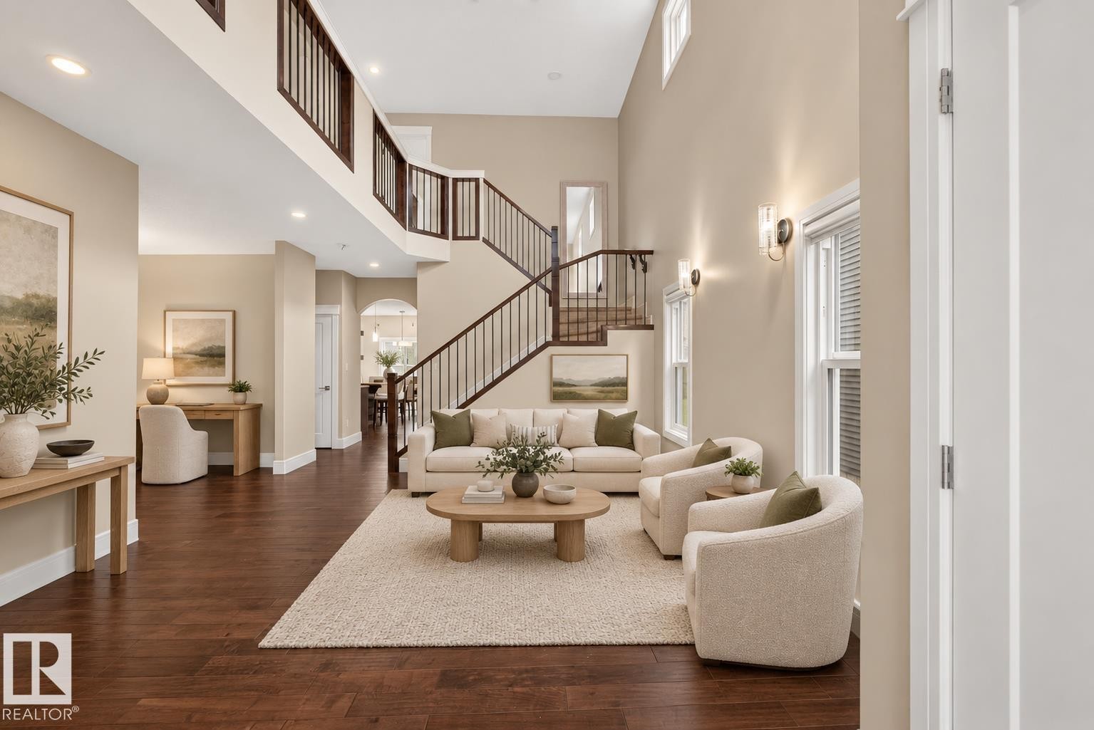 Two-story living area featuring wood-finish flooring, a grand staircase with wrought iron balusters, and a second-story landing - 7014 Chivers Loop Sw, Edmonton, AB