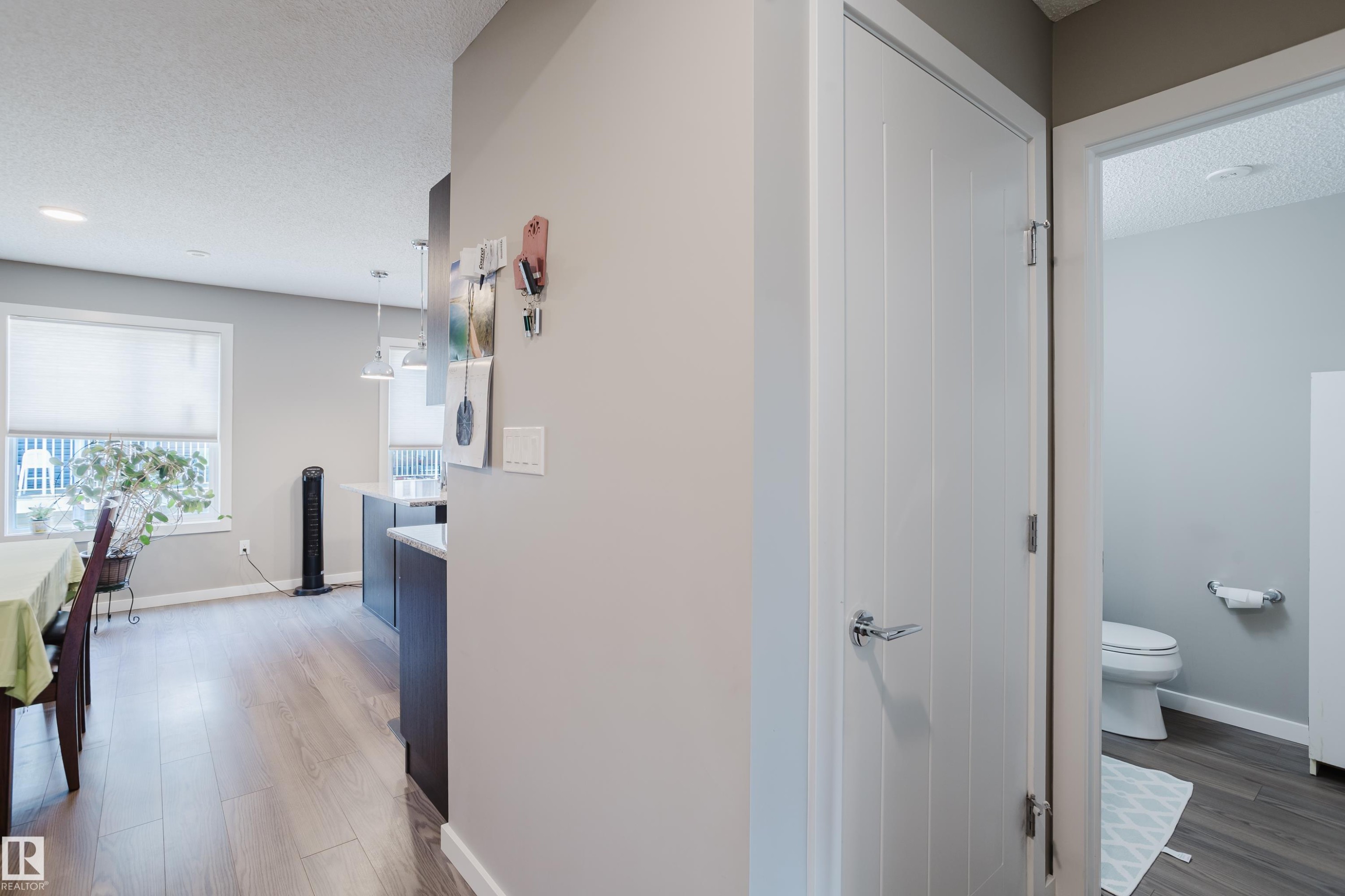 Hallway featuring a contemporary white door with chrome hardware, wood-finish flooring, and light gray wall paint - #28 2215 24 St Nw, Edmonton, AB - Indoor