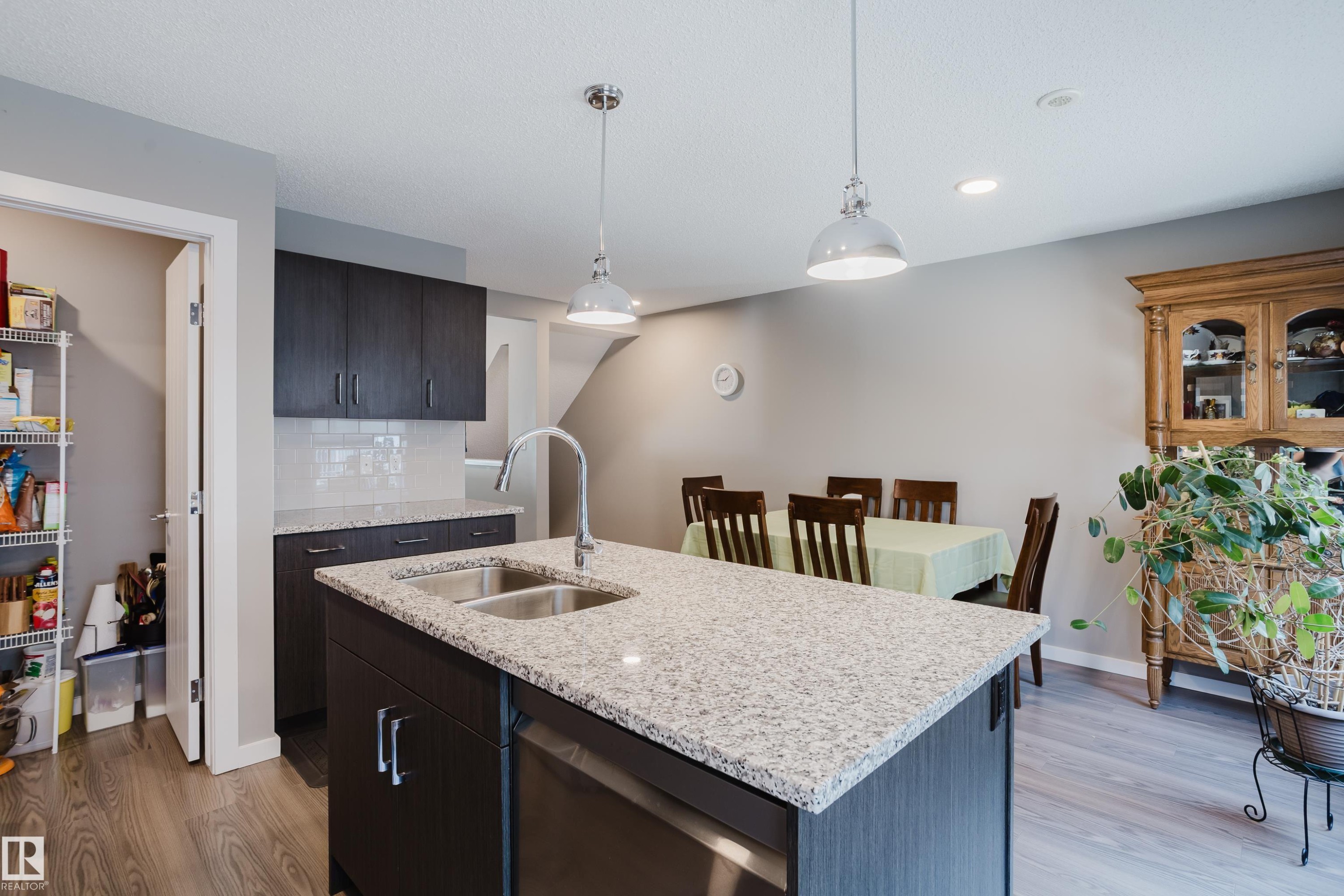 Kitchen island with a double basin stainless steel sink, a chrome faucet, and pendant lighting - #28 2215 24 St Nw, Edmonton, AB - Indoor Photo Showing Kitchen With Double Sink