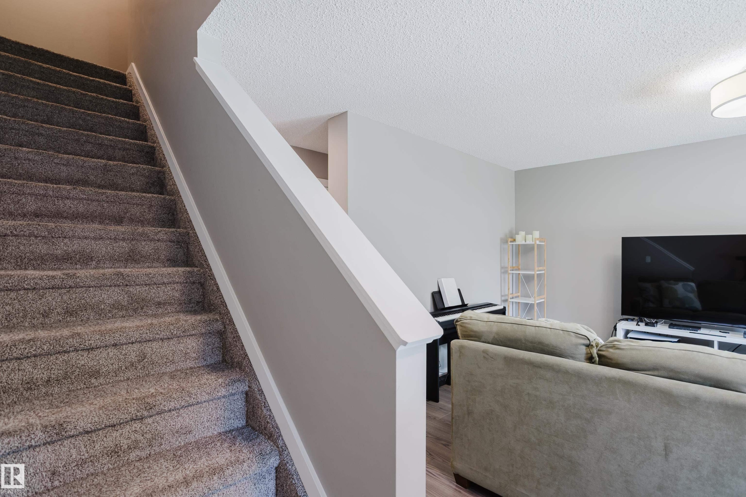 Carpeted staircase with white trim, light gray wall paint, and textured ceiling - #28 2215 24 St Nw, Edmonton, AB - Indoor Photo Showing Other Room