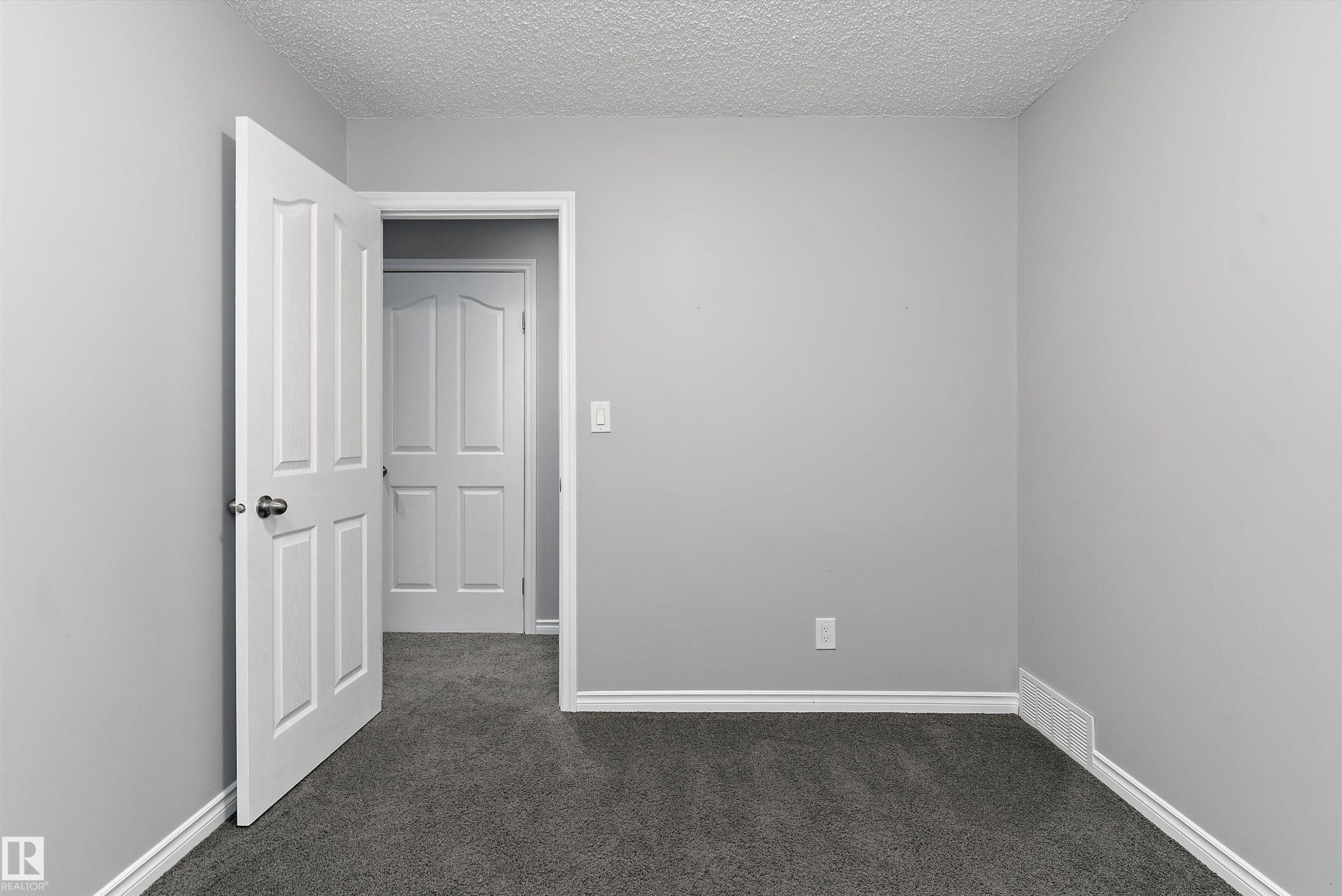 Neutral gray wall paint with white trim, dark gray carpeting, and white paneled doors - 20845 92A Avenue Nw, Edmonton, AB - Indoor Photo Showing Other Room