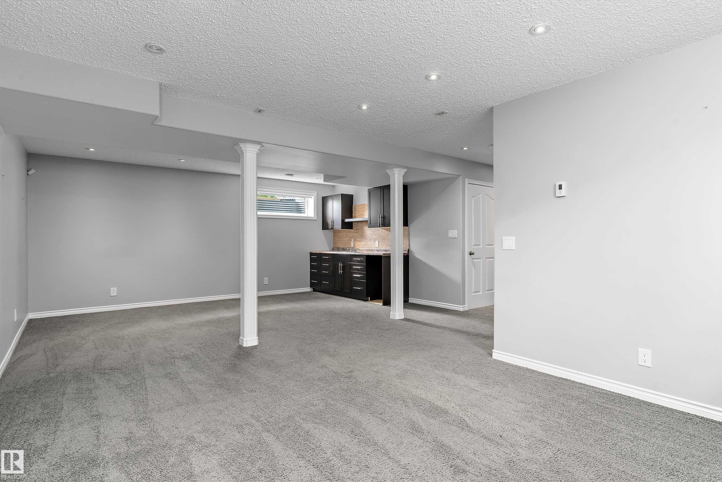 Expansive carpeted area featuring recessed lighting, a built-in wet bar with dark cabinetry, a neutral-toned backsplash, and an egress window - 20845 92A Avenue Nw, Edmonton, AB - Indoor