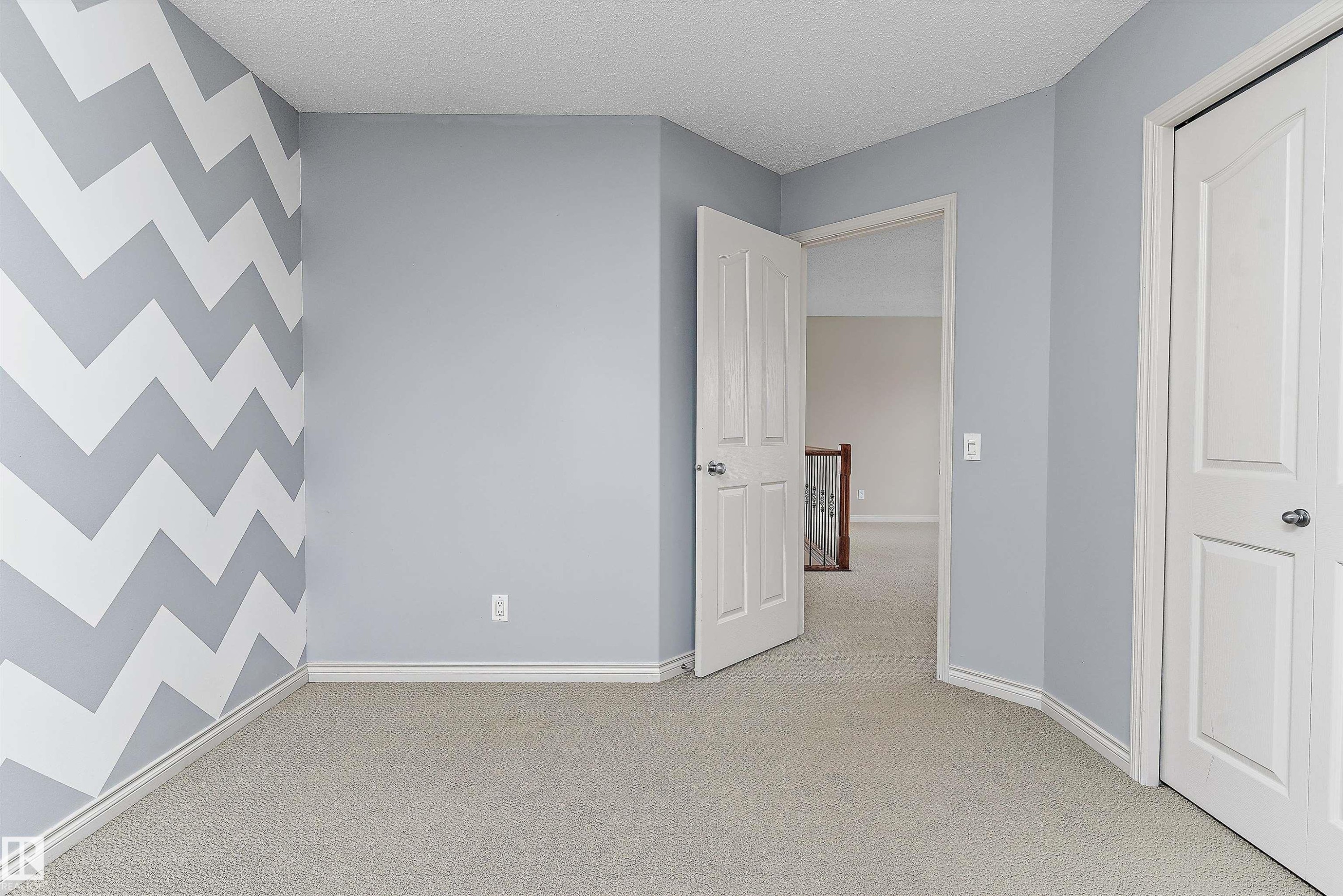 Light-toned carpet flooring, a decorative accent wall, paneled interior doors, and white trim work - 20845 92A Avenue Nw, Edmonton, AB - Indoor Photo Showing Other Room