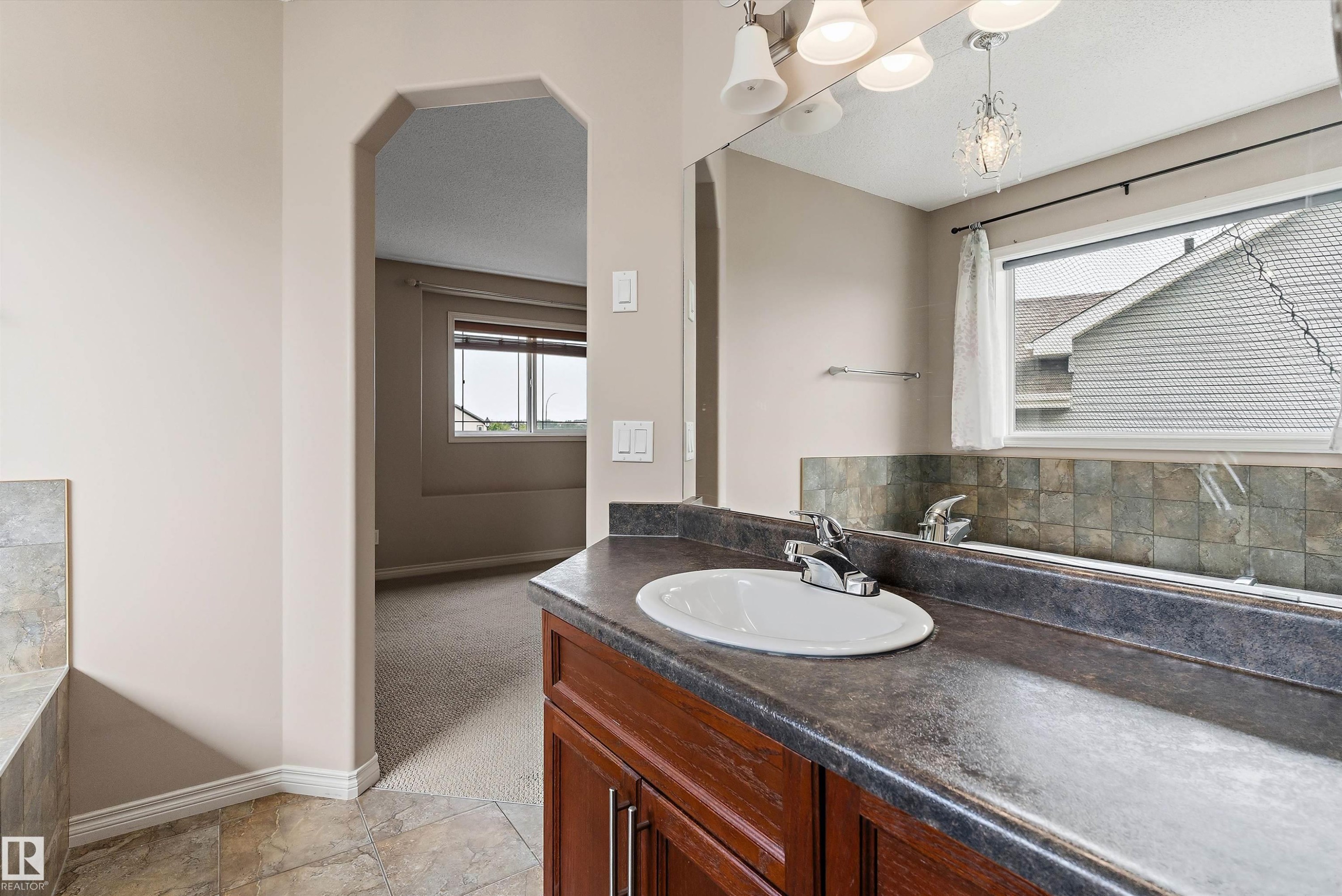 Vanity with a laminate countertop, undermount sink, and wood-finish cabinetry - 20845 92A Avenue Nw, Edmonton, AB - Indoor Photo Showing Bathroom