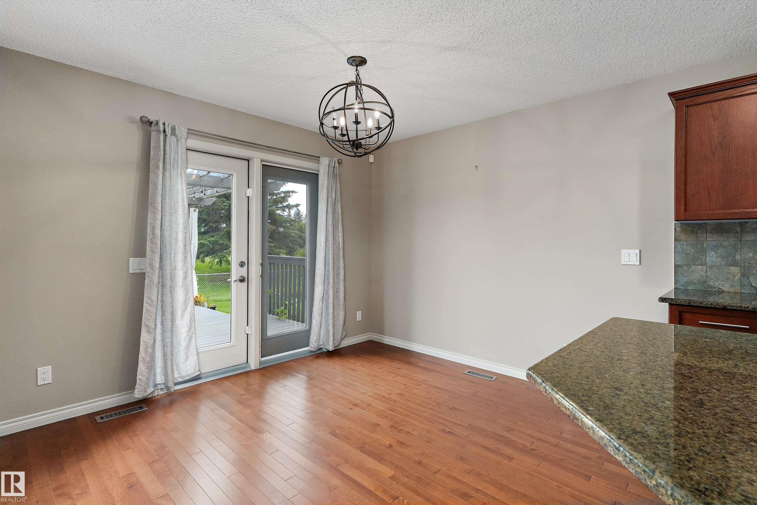Hardwood flooring, double patio doors, orb-style chandelier, granite countertop, and tiled backsplash - 20845 92A Avenue Nw, Edmonton, AB - Indoor Photo Showing Other Room