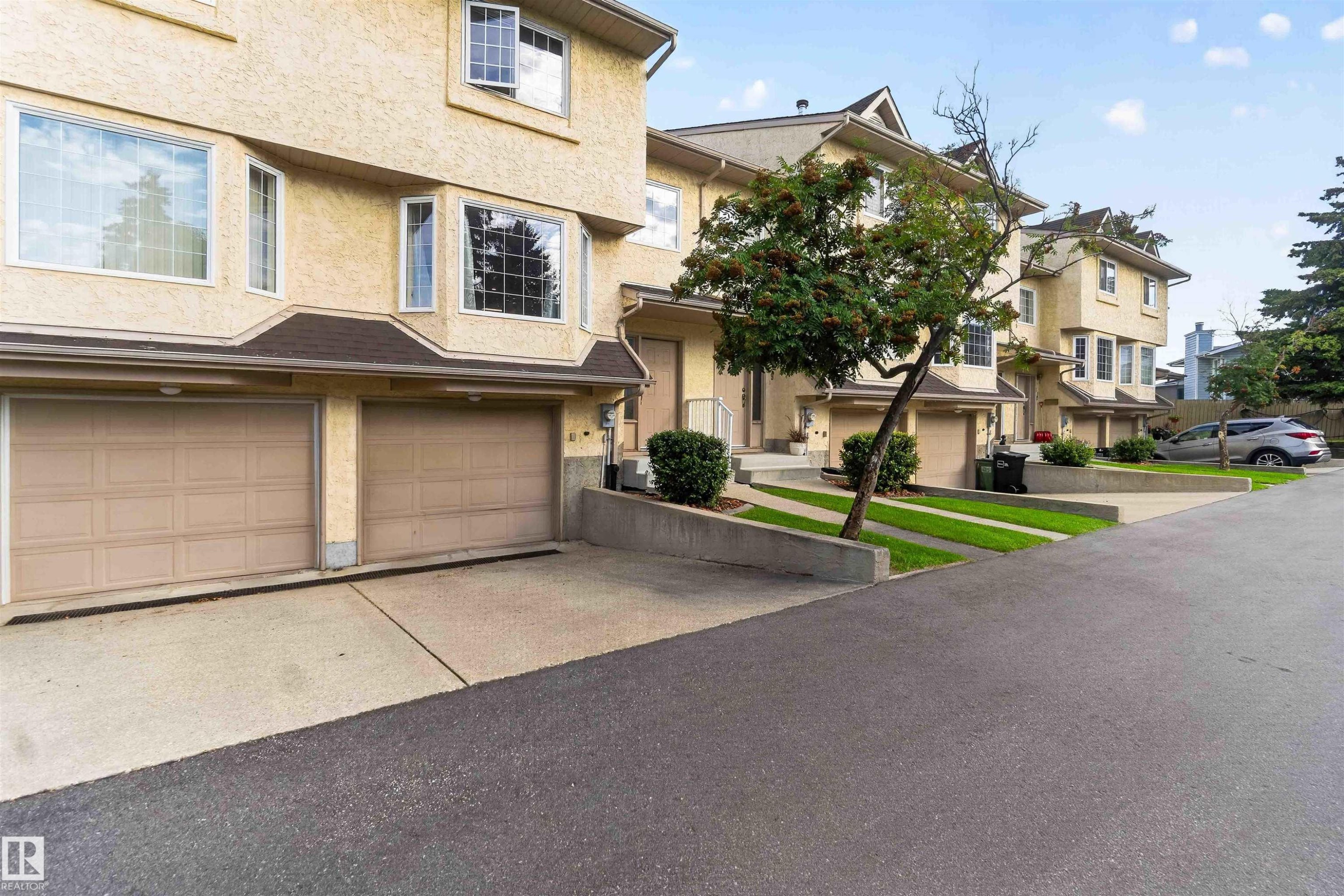 Two-car garage with panel doors and concrete driveway - #28 3645 145 Av Nw, Edmonton, AB - Outdoor With Facade