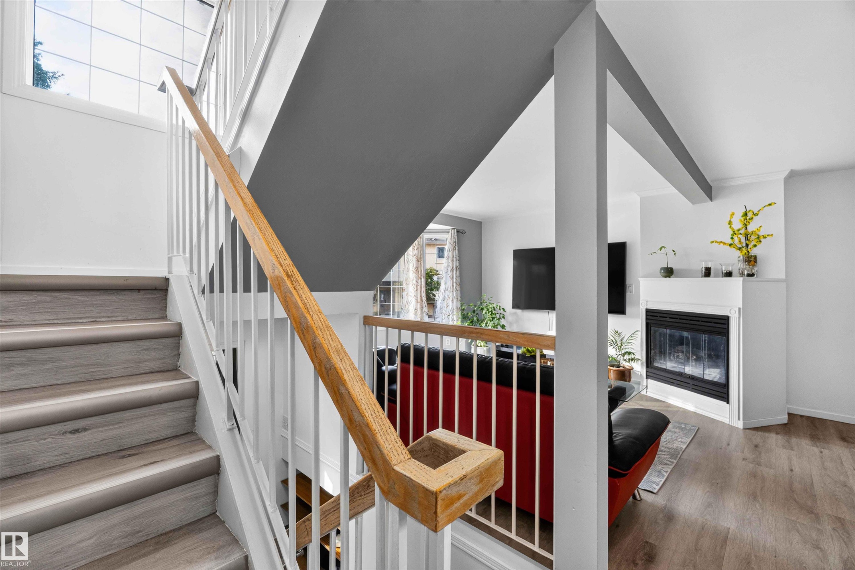 Wood-finish stairs with white balusters, natural wood handrail, and upper window - #28 3645 145 Av Nw, Edmonton, AB - Indoor Photo Showing Other Room