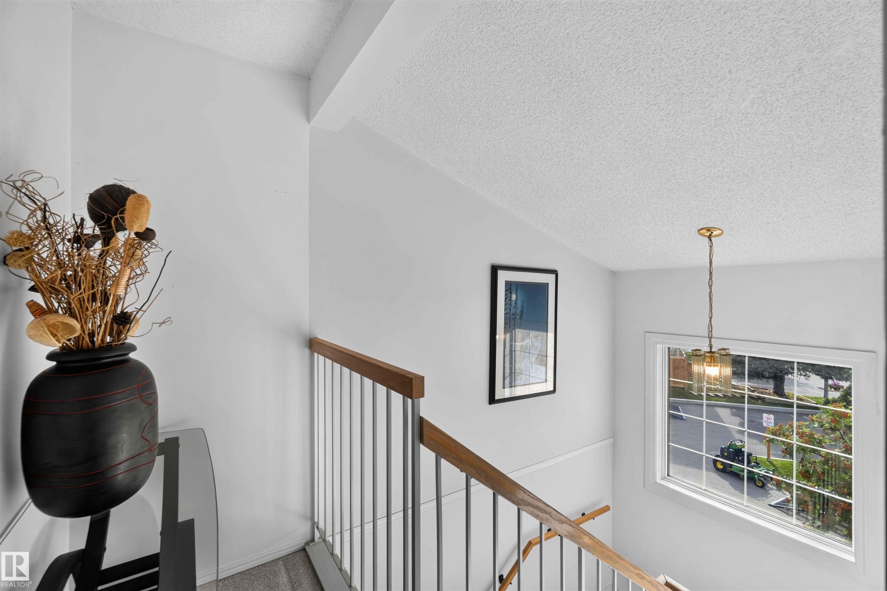 Stairwell featuring a wood handrail, metal balusters, and a window with natural light - #28 3645 145 Av Nw, Edmonton, AB - Indoor Photo Showing Other Room