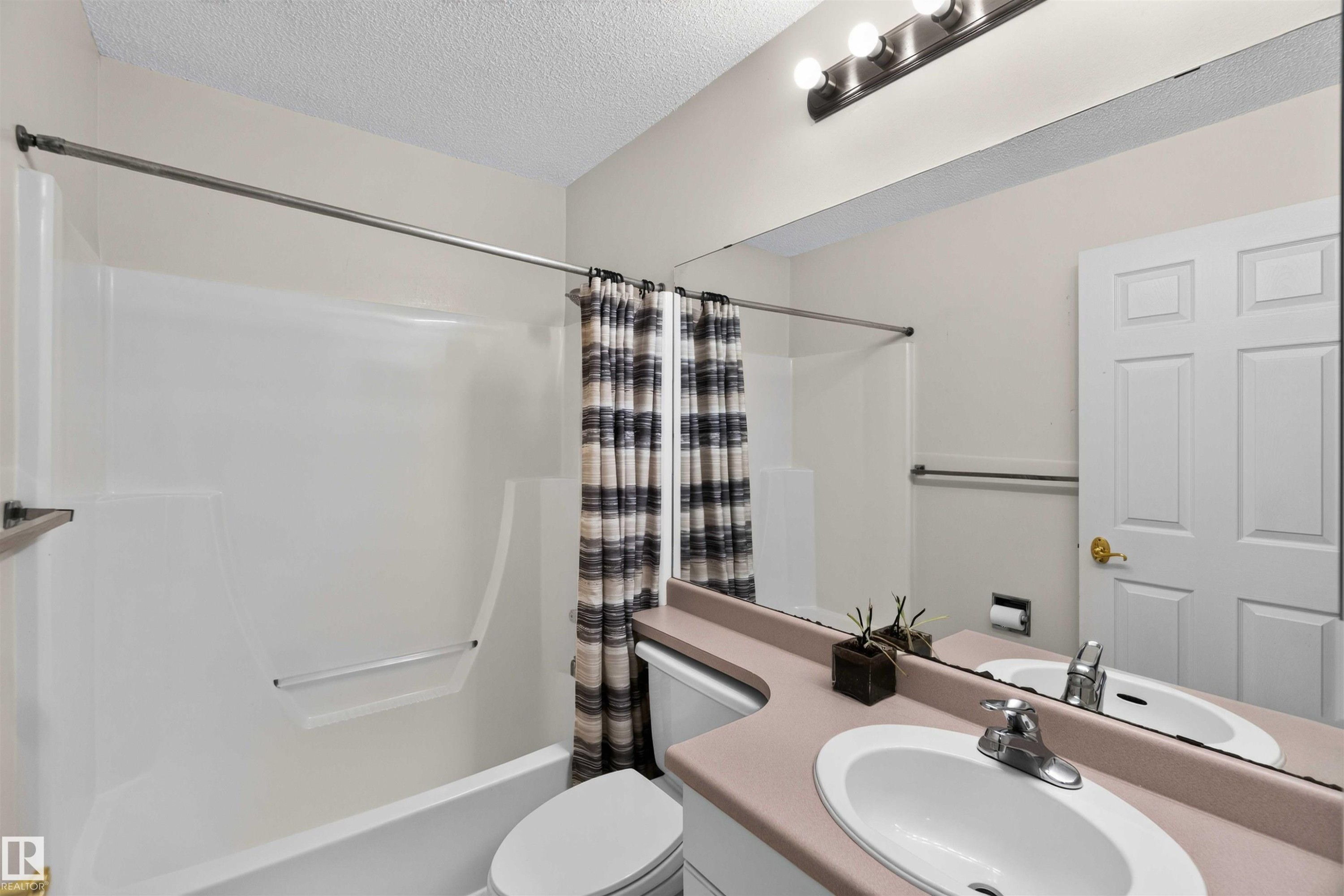 Single-piece vanity with integrated oval sink, full-width wall mirror, and three-bulb vanity light - #28 3645 145 Av Nw, Edmonton, AB - Indoor Photo Showing Bathroom