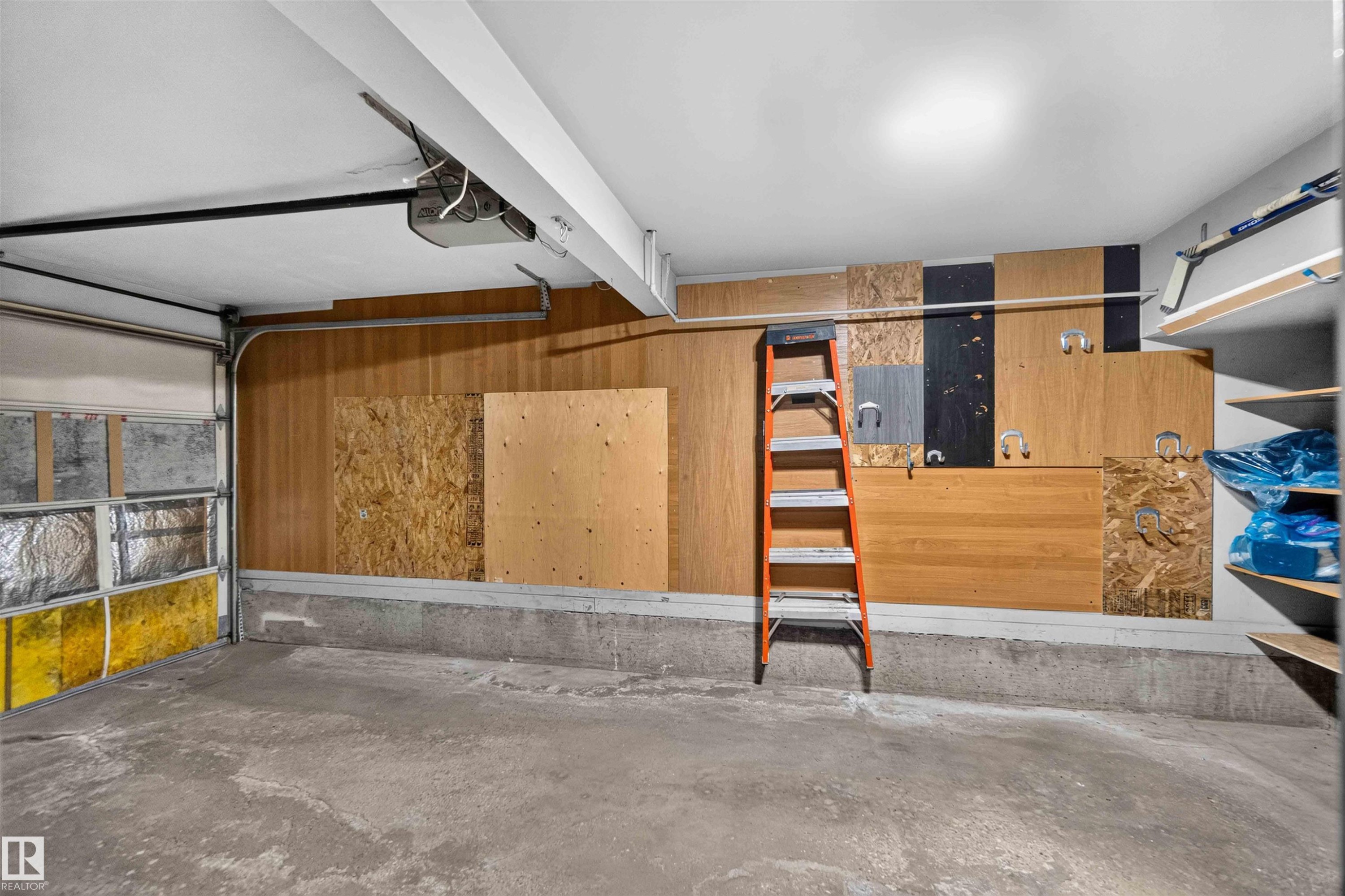 Concrete flooring, wood paneling, overhead lighting, garage door, built-in shelving - #28 3645 145 Av Nw, Edmonton, AB - Indoor
