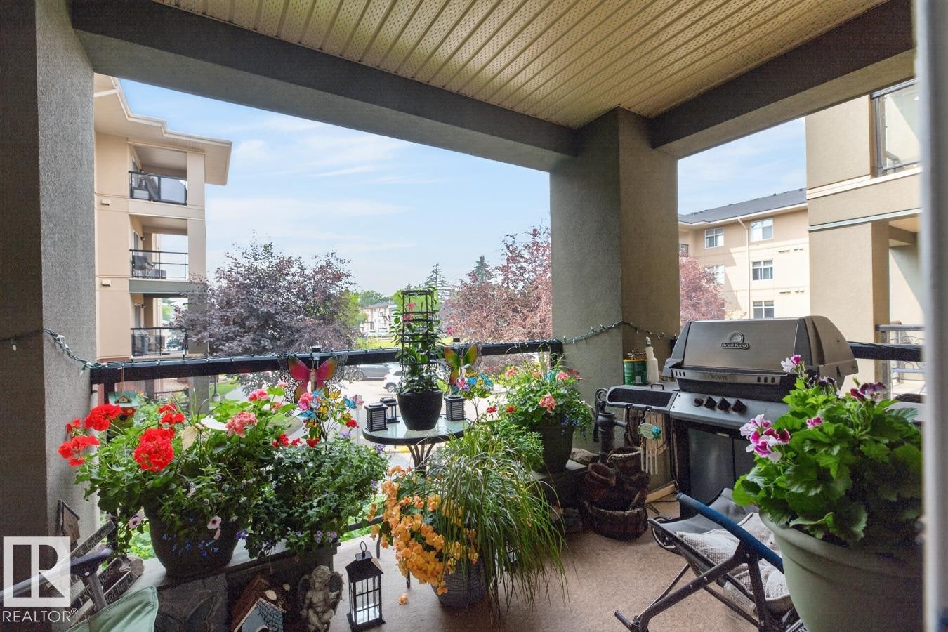 Covered balcony featuring a textured ceiling, a metal railing, and an outdoor light string - #210 7909 71 St Nw, Edmonton, AB - Outdoor With Balcony With Exterior