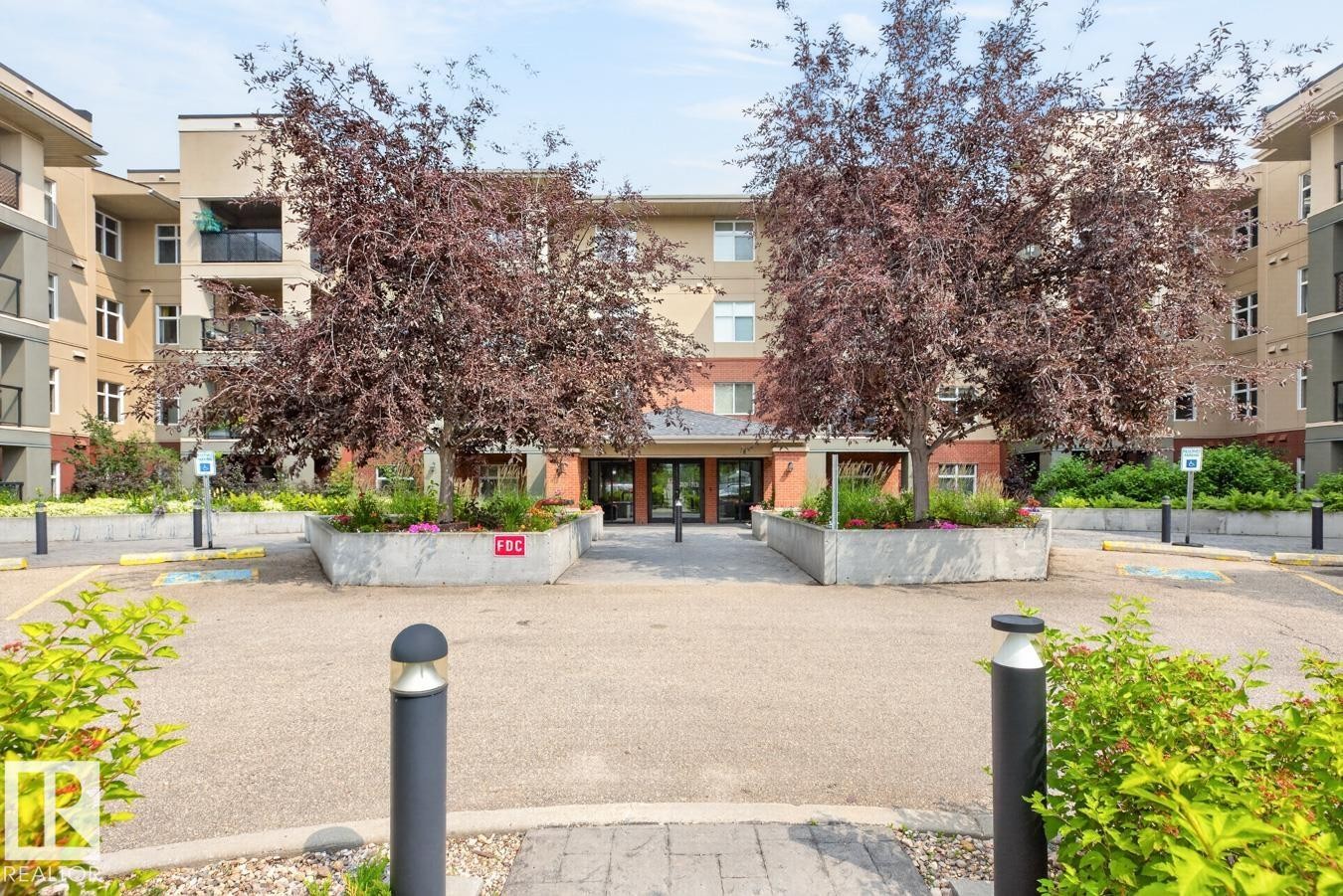 Multi-story building featuring balconies, mature trees, and landscaped planter boxes - #210 7909 71 St Nw, Edmonton, AB - Outdoor With Balcony