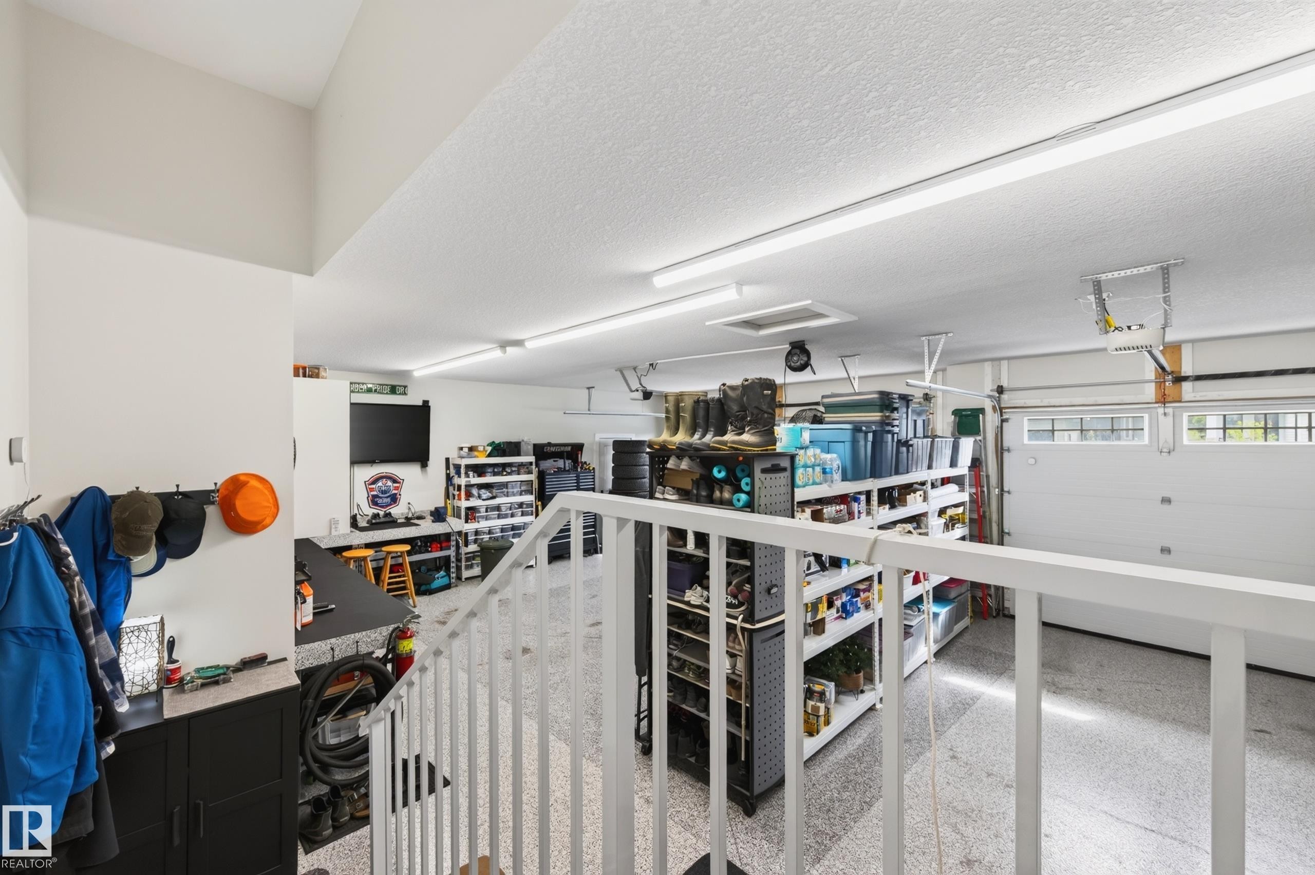 heated triple garage with polyaspartic coating on floors/workbench/stairs. Hot and cold taps, cabinets above work bench, upgraded door seals, slat wall, floor drains - 91 Harvest Crescent, Ardrossan, AB - Indoor Photo Showing Garage