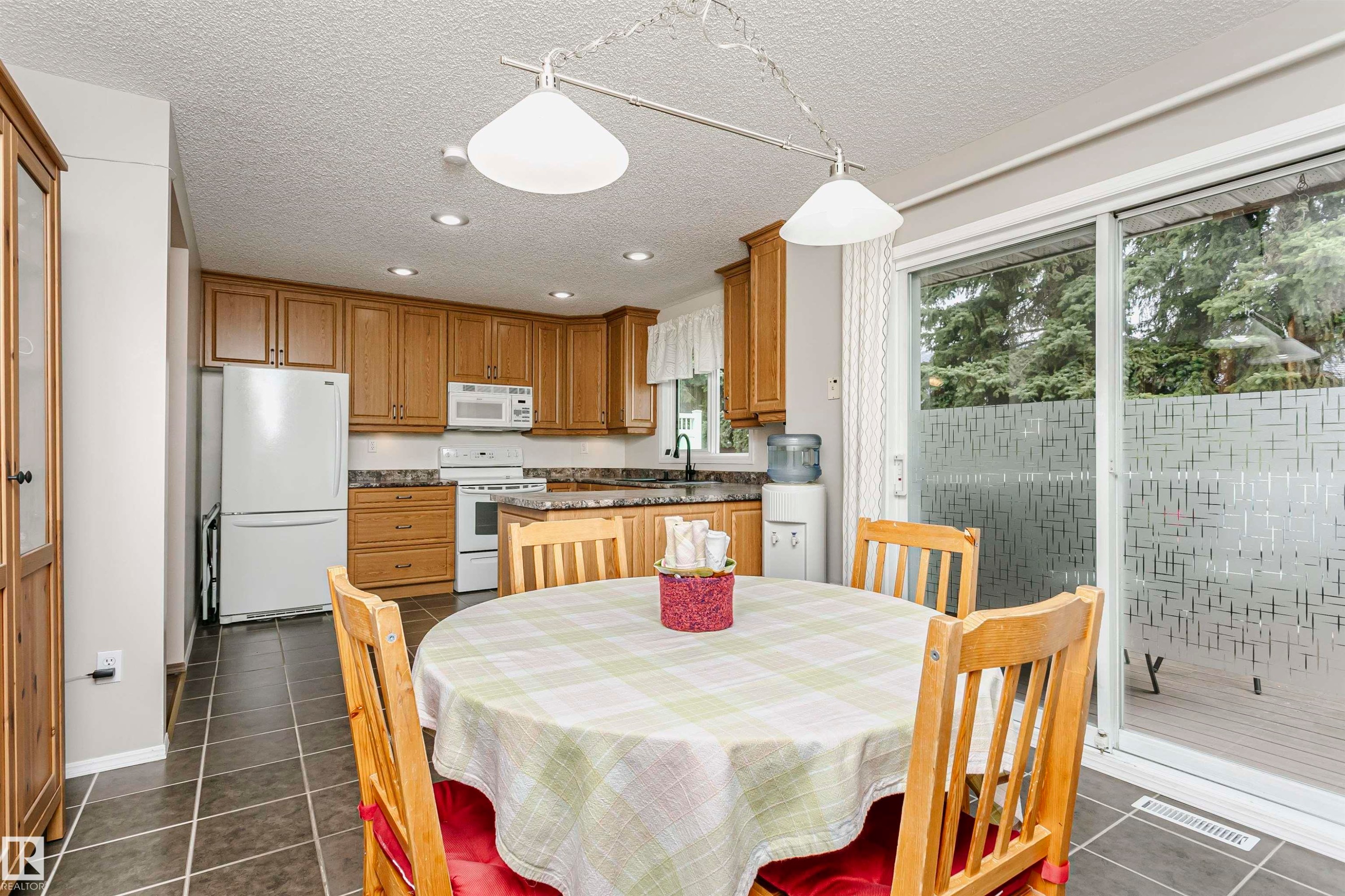 Kitchen with wood cabinetry, dark stone-finish countertops, white appliances, and recessed lighting - #42 9630 176 St Nw, Edmonton, AB - Indoor Photo Showing Dining Room