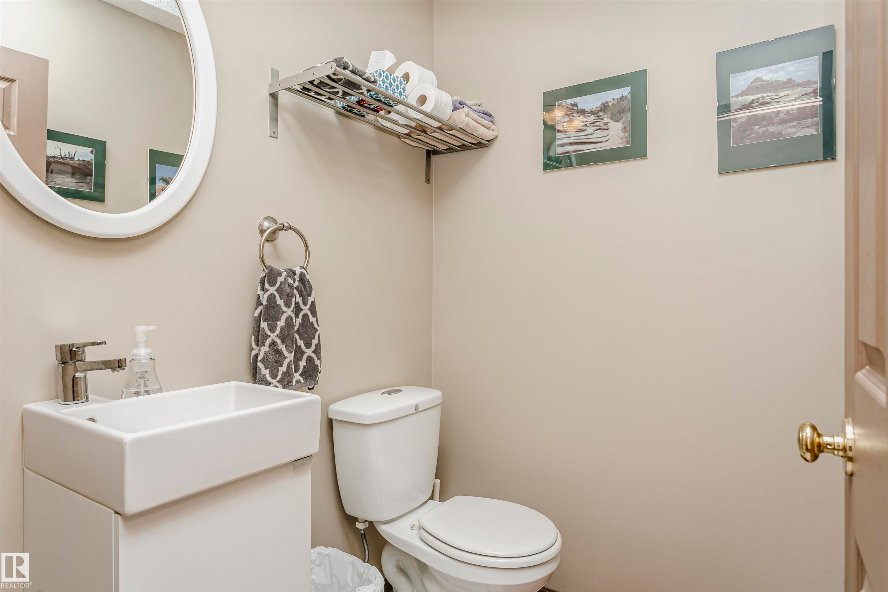 Pedestal sink with a rectangular basin, chrome faucet, and oval mirror - #42 9630 176 St Nw, Edmonton, AB - Indoor Photo Showing Bathroom