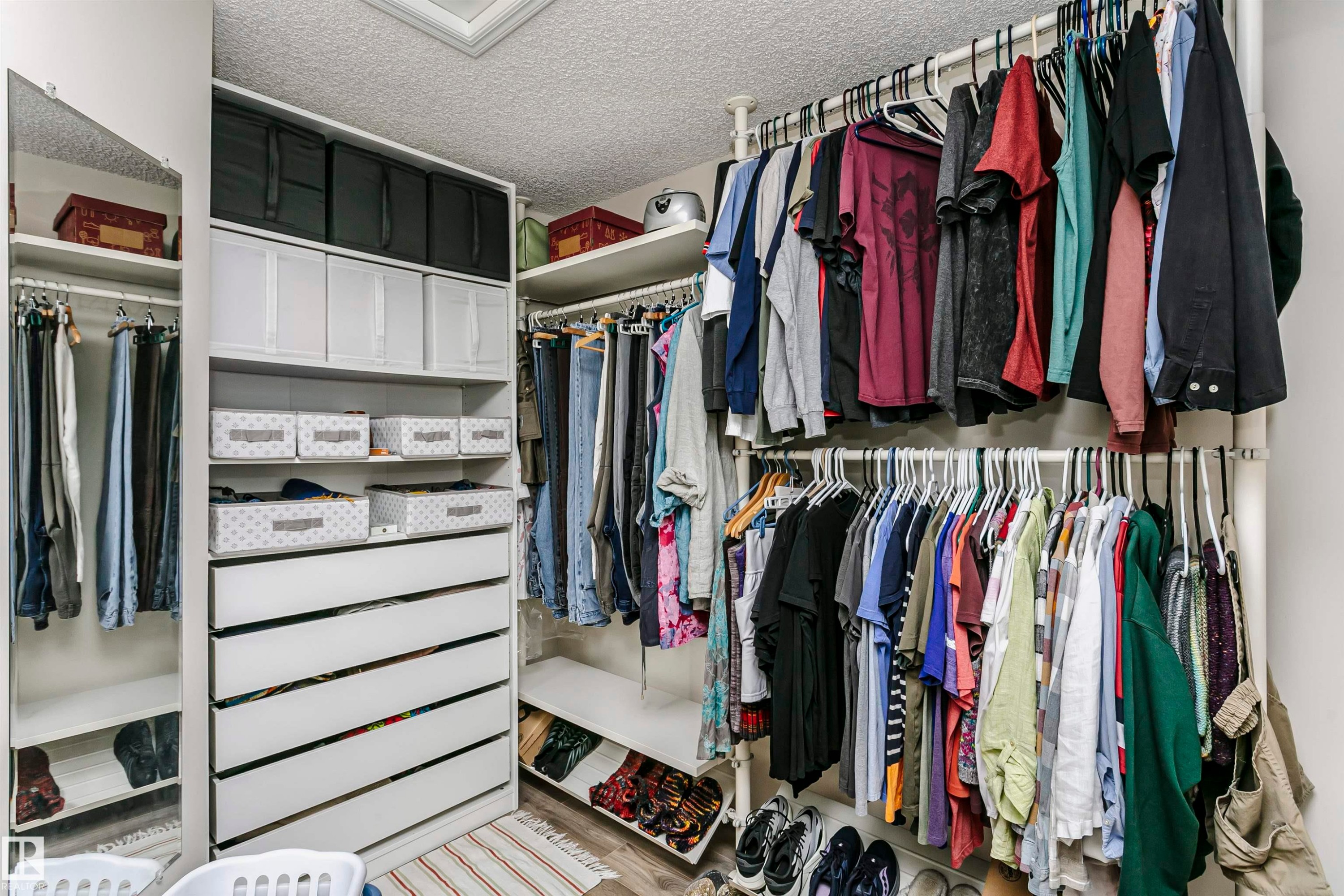 Custom built-in closet system featuring multiple hanging rods, integrated shelving, and white drawer storage - #42 9630 176 St Nw, Edmonton, AB - Indoor With Storage