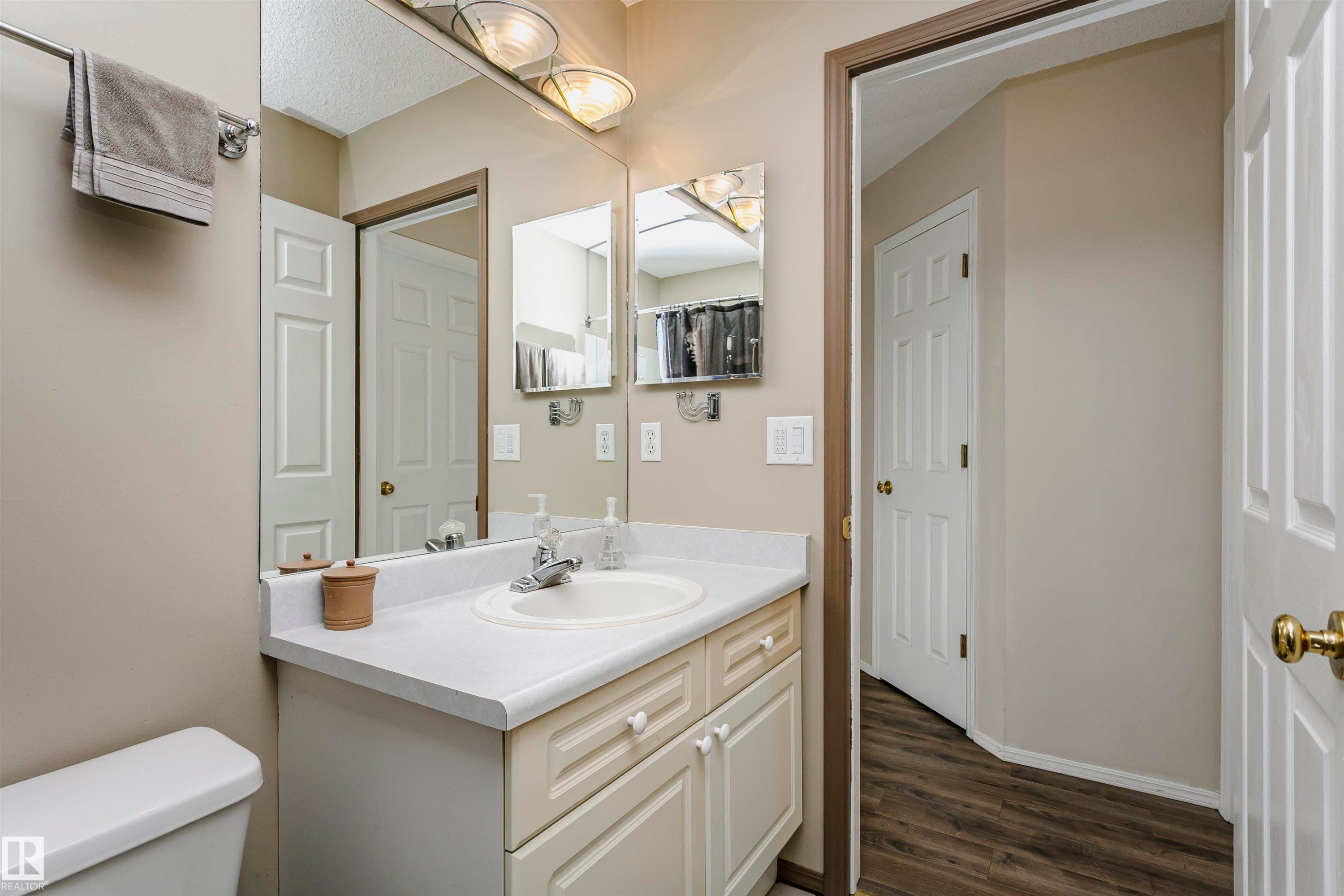 White vanity with integrated sink, chrome faucet, and overhead lighting - #42 9630 176 St Nw, Edmonton, AB - Indoor Photo Showing Bathroom