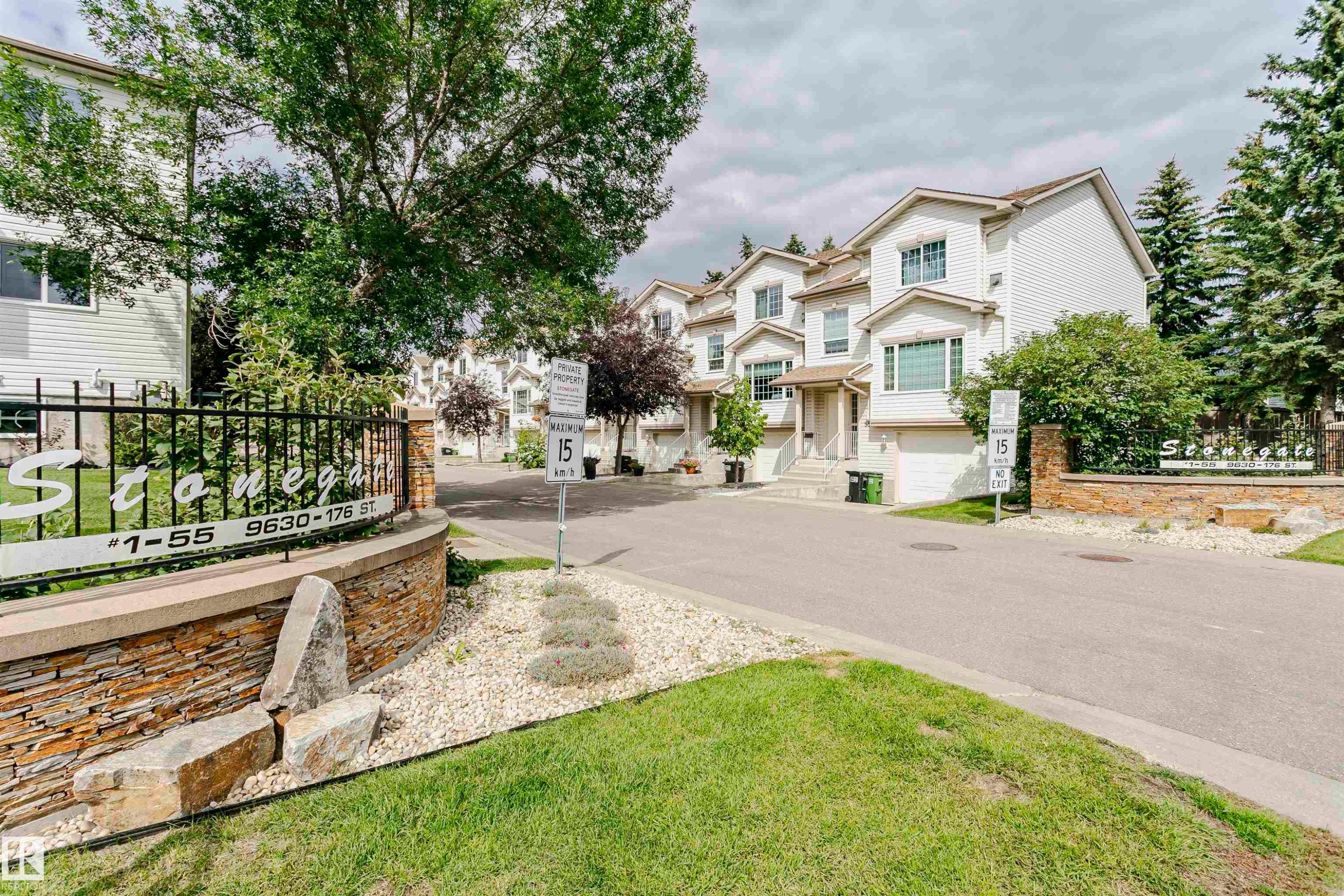 Private property entrance with stone veneer wall, wrought iron fencing, and mature landscaping - #42 9630 176 St Nw, Edmonton, AB - Outdoor With Facade