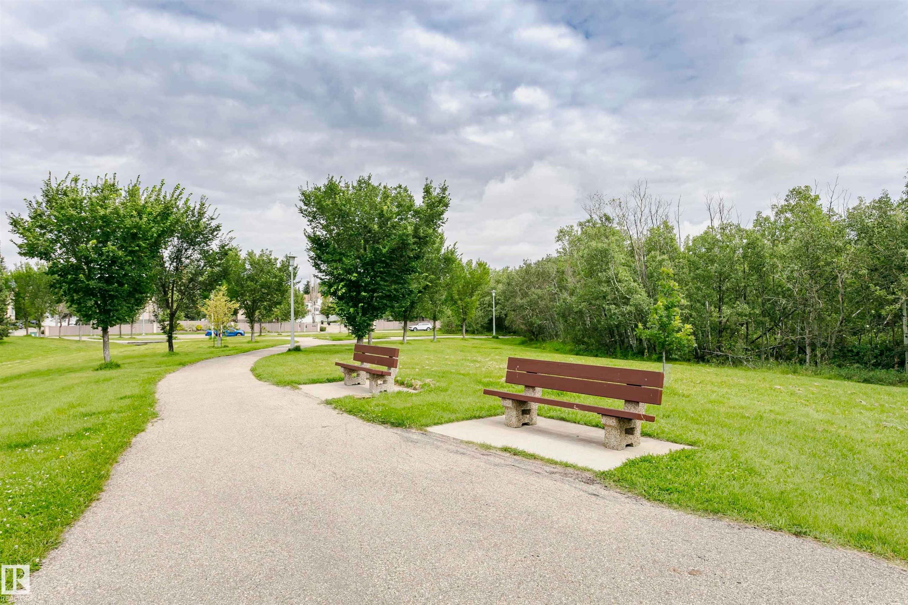 Paved walking path winding through a park setting with two brown benches - #42 9630 176 St Nw, Edmonton, AB - Outdoor