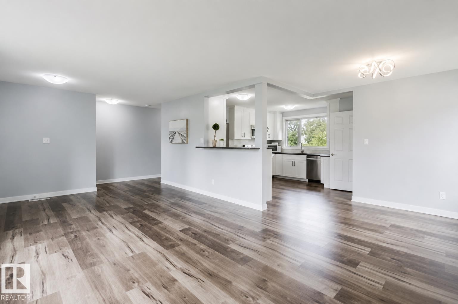 Wood-finish flooring throughout, recessed lighting, and a kitchen featuring white cabinetry, a double-basin sink, and stainless steel appliances - 11420 46 Avenue Nw, Edmonton, AB - Indoor