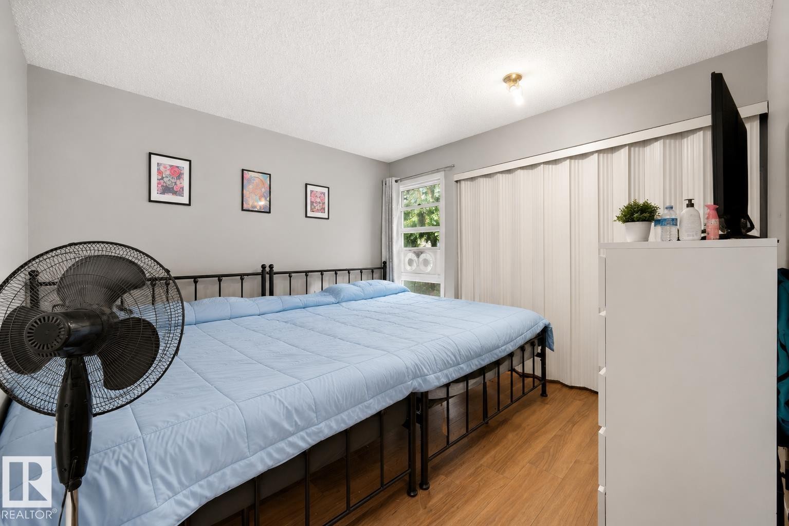 Wood-finish flooring, light gray wall paint, and a built-in accordion door wardrobe - #44 1415 62 St Nw, Edmonton, AB - Indoor Photo Showing Bedroom