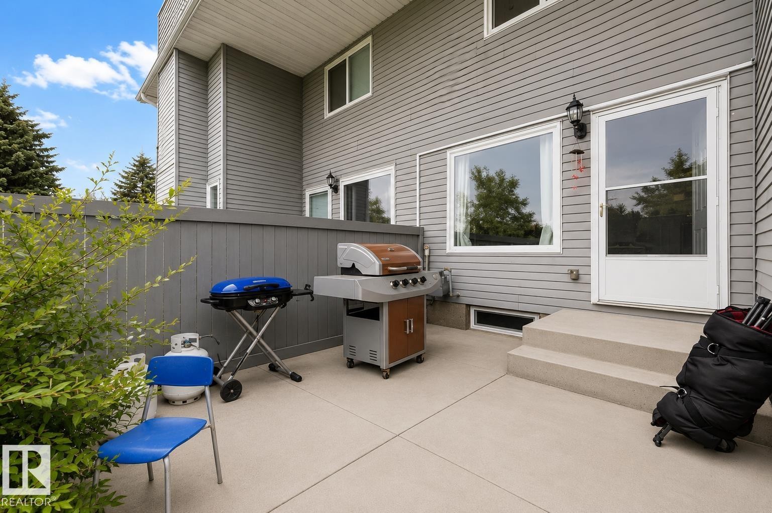 Paved patio area, privacy fence, exterior siding, exterior light fixture, and large windows - #44 1415 62 St Nw, Edmonton, AB - Outdoor With Deck Patio Veranda With Exterior