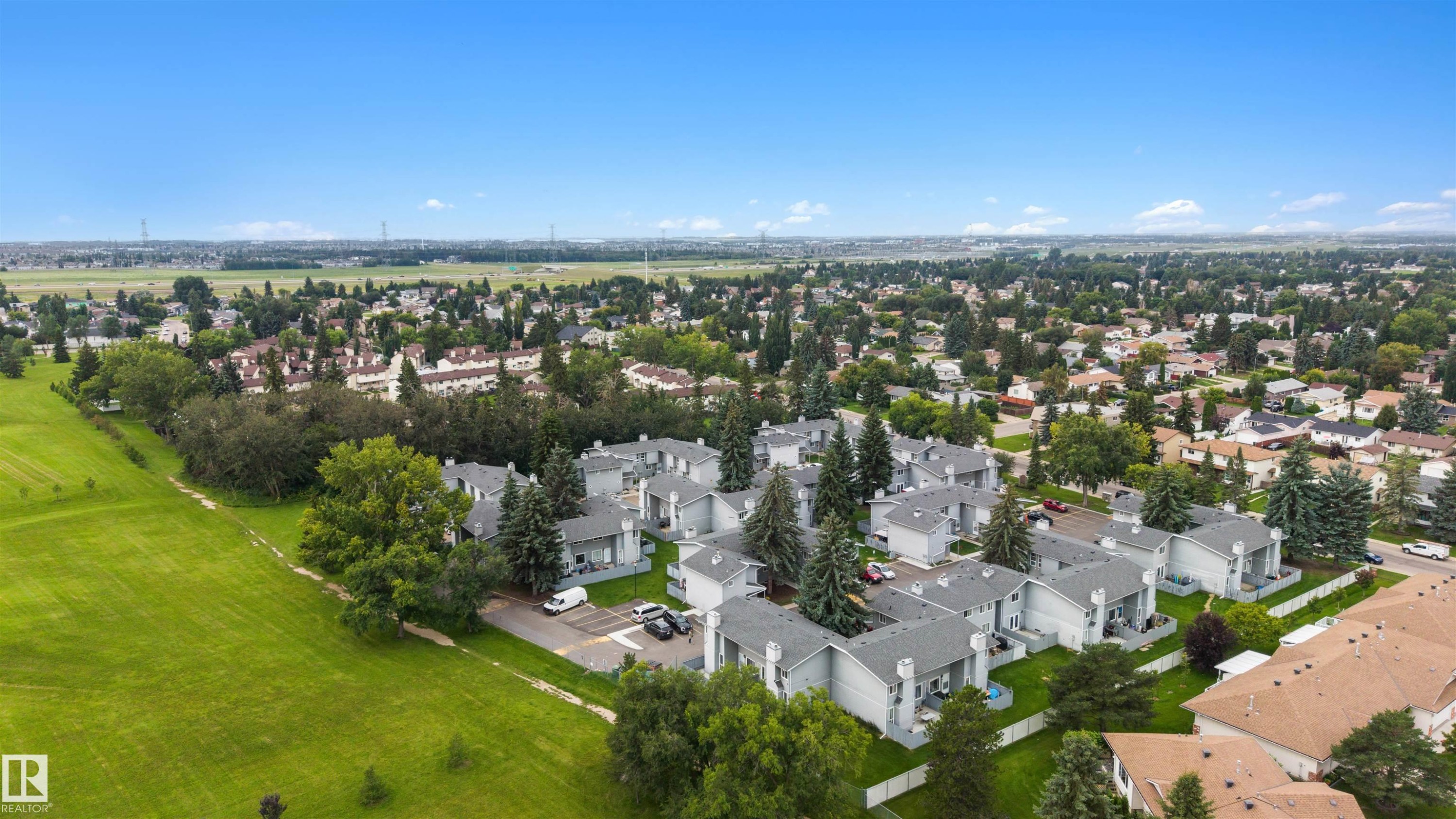 Residential area featuring multiple townhome-style buildings with light gray siding and dark gray shingle roofs - #44 1415 62 St Nw, Edmonton, AB - Outdoor With View